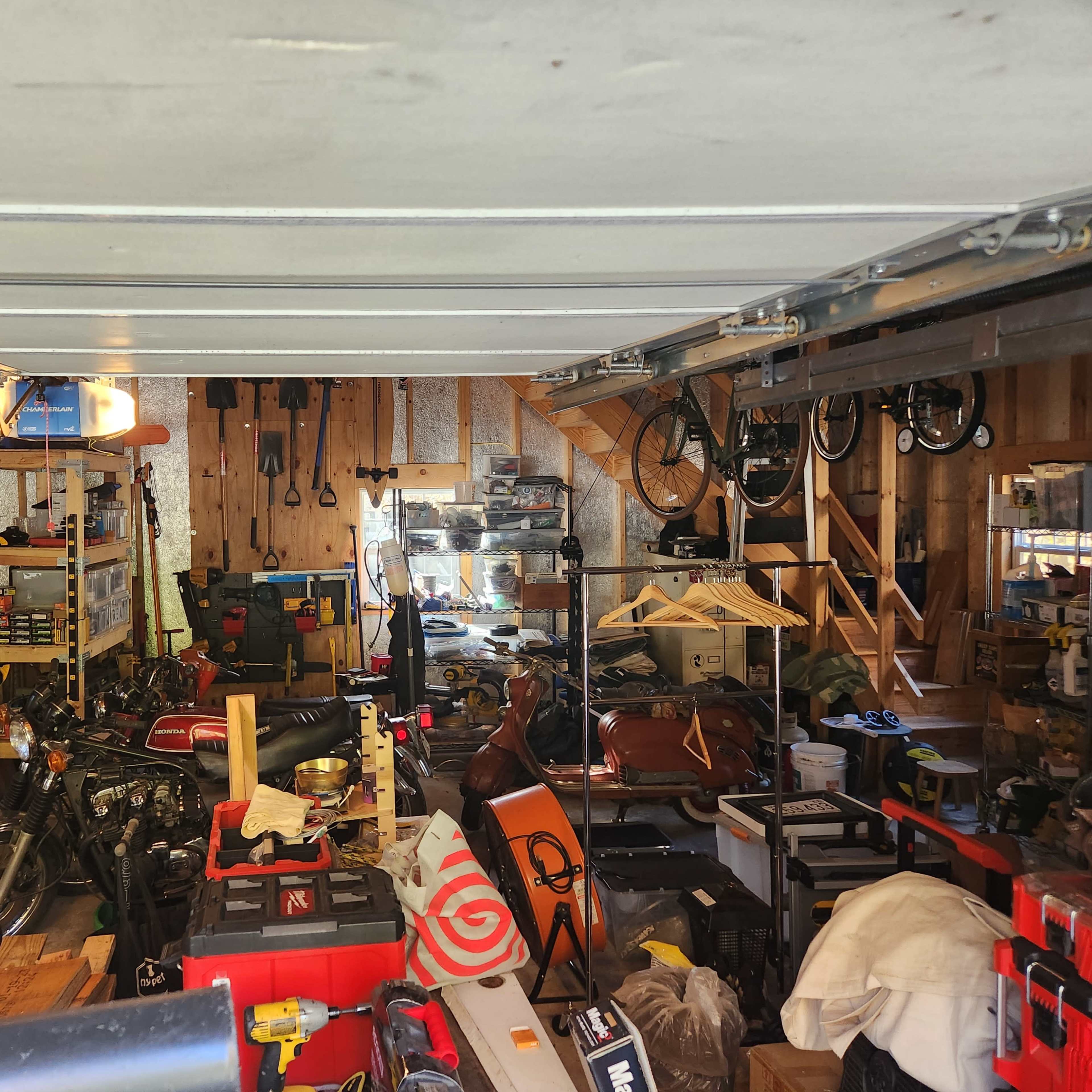 A cluttered garage filled with various tools, bicycles, and equipment.