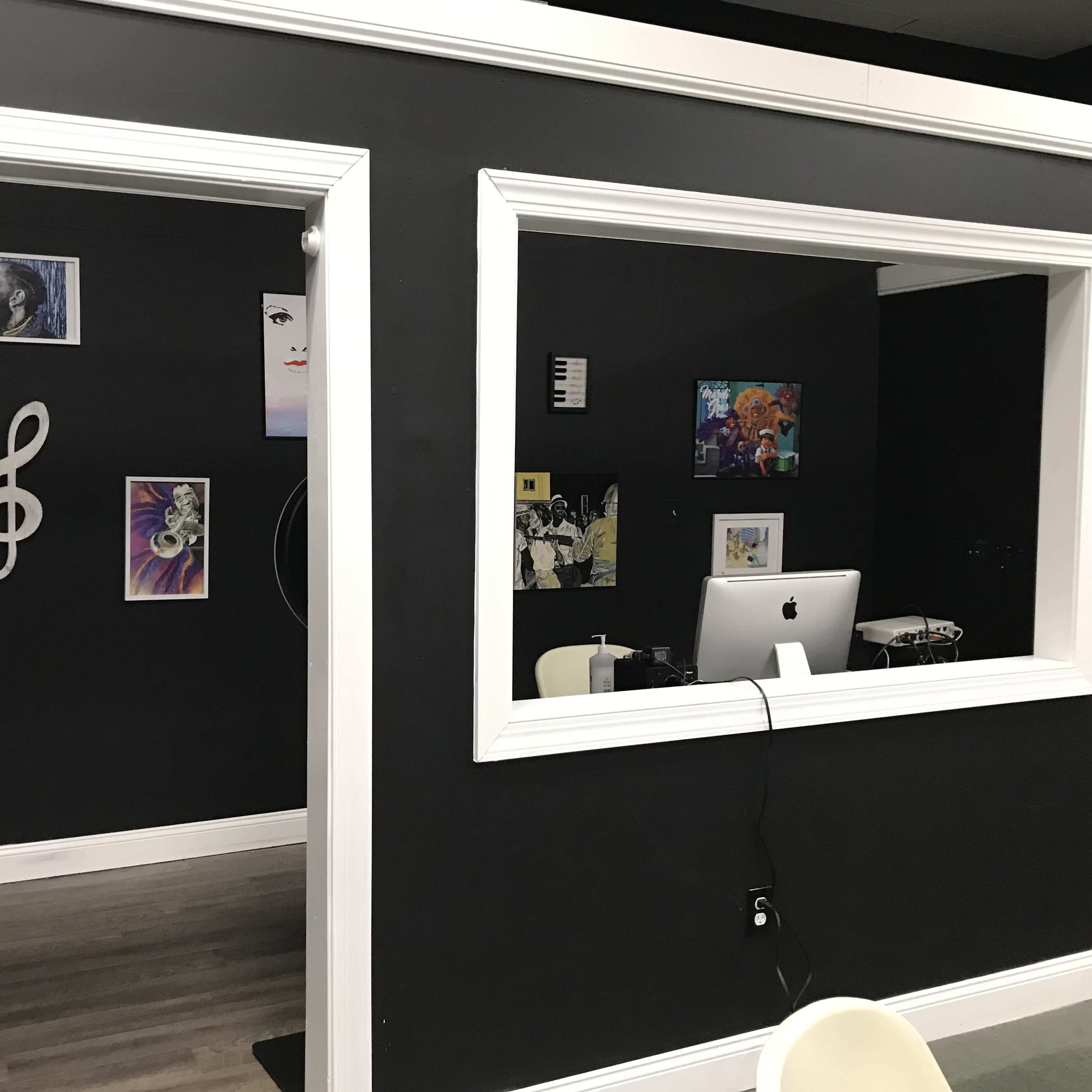 Two openings in a black wall, each displaying framed artwork, with a computer setup visible in one of the rooms.