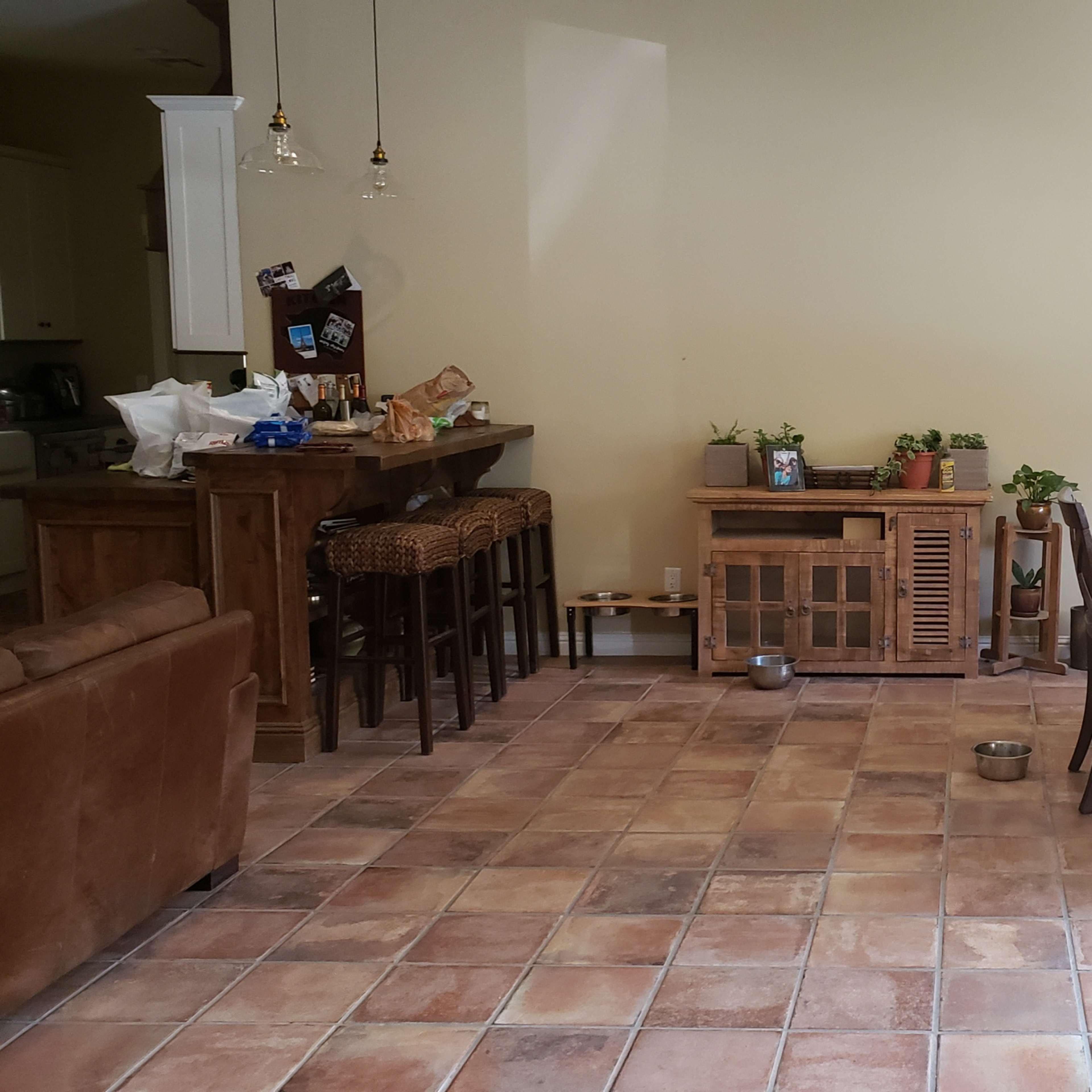 A spacious open-concept living and dining area with a kitchen bar, a dining table with chairs, and a side cabinet against a wall.