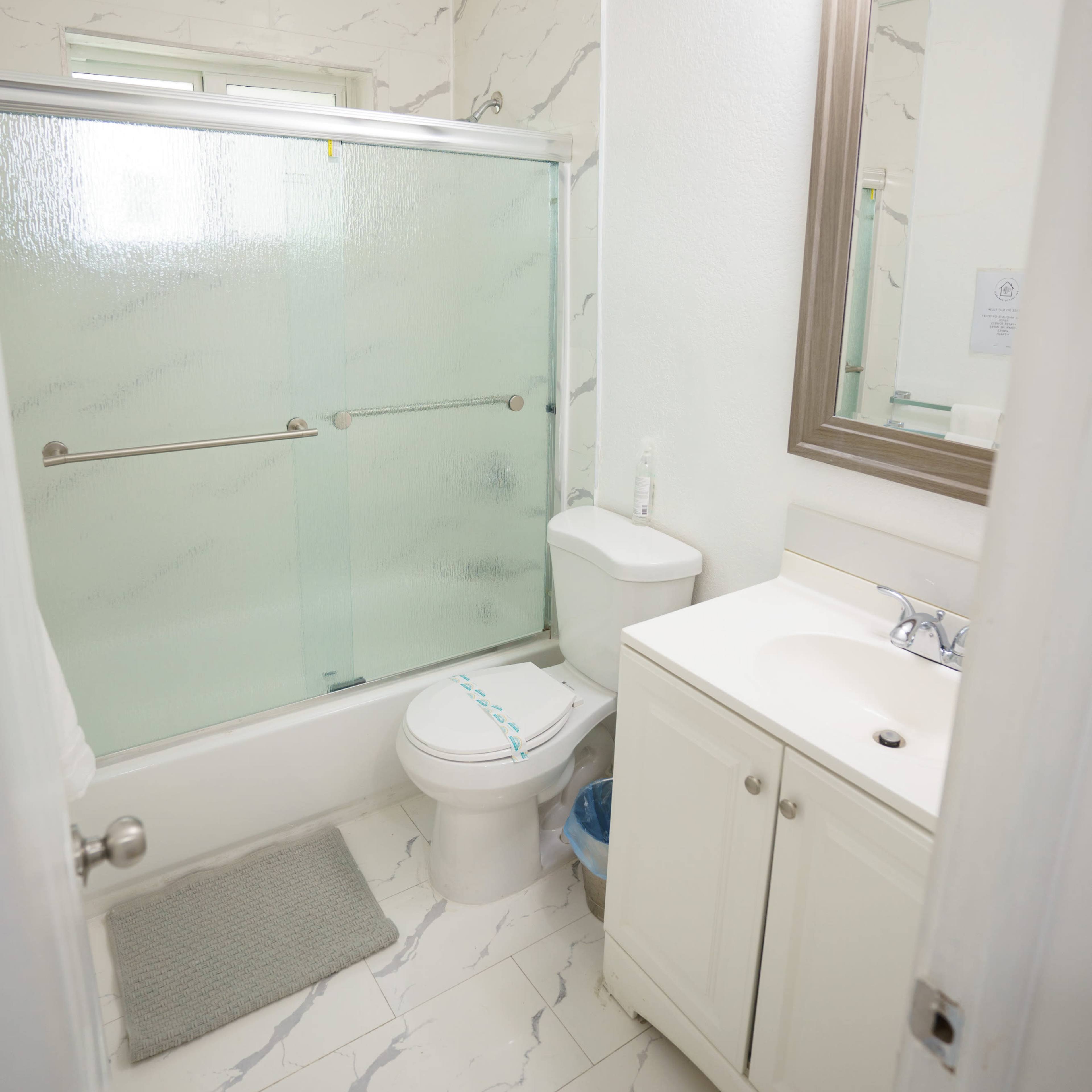 A modern bathroom featuring a shower with a glass door, a toilet, a vanity with a sink, and tile flooring.