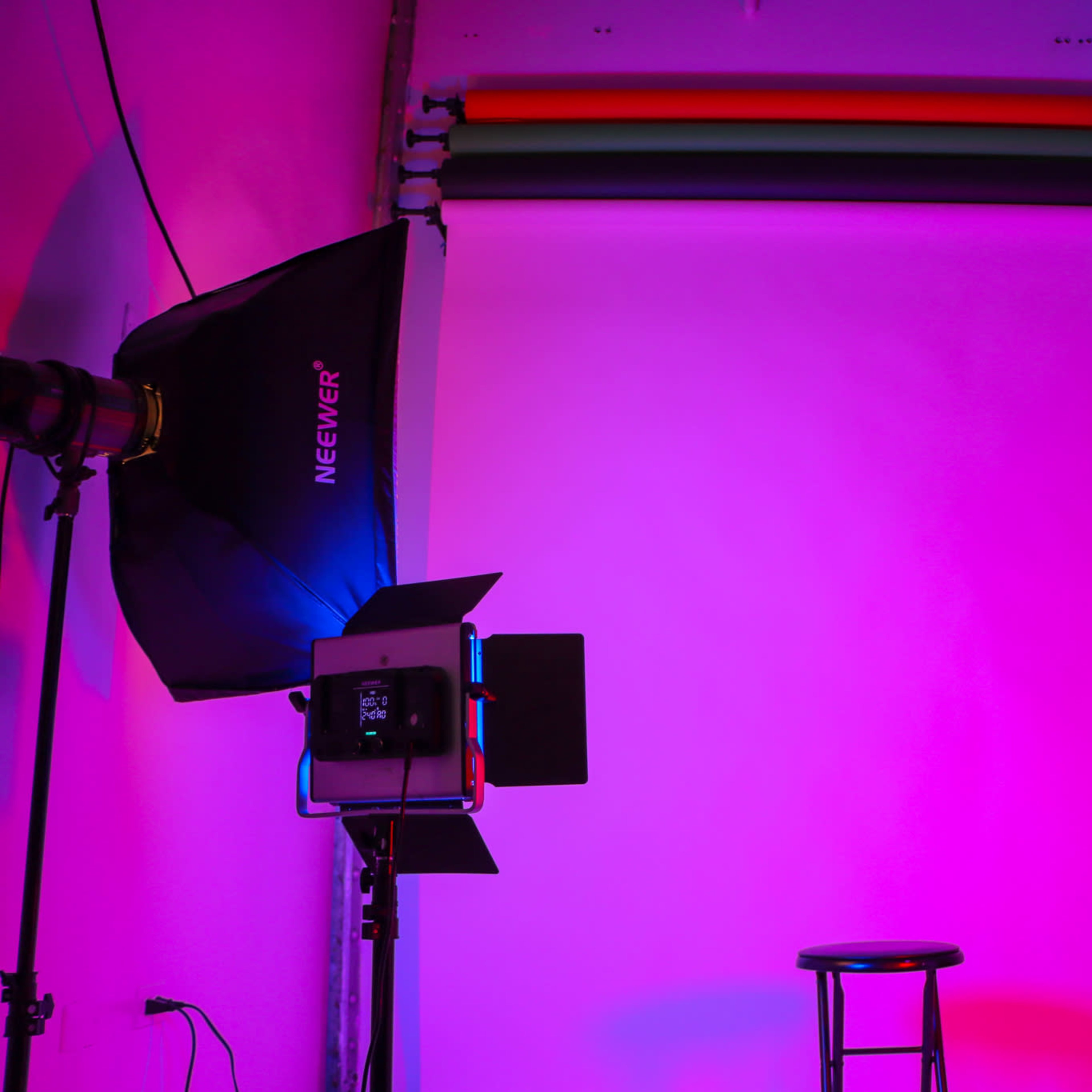 A photography studio setup with two lights on either side, a stool in the center, and a colored backdrop.