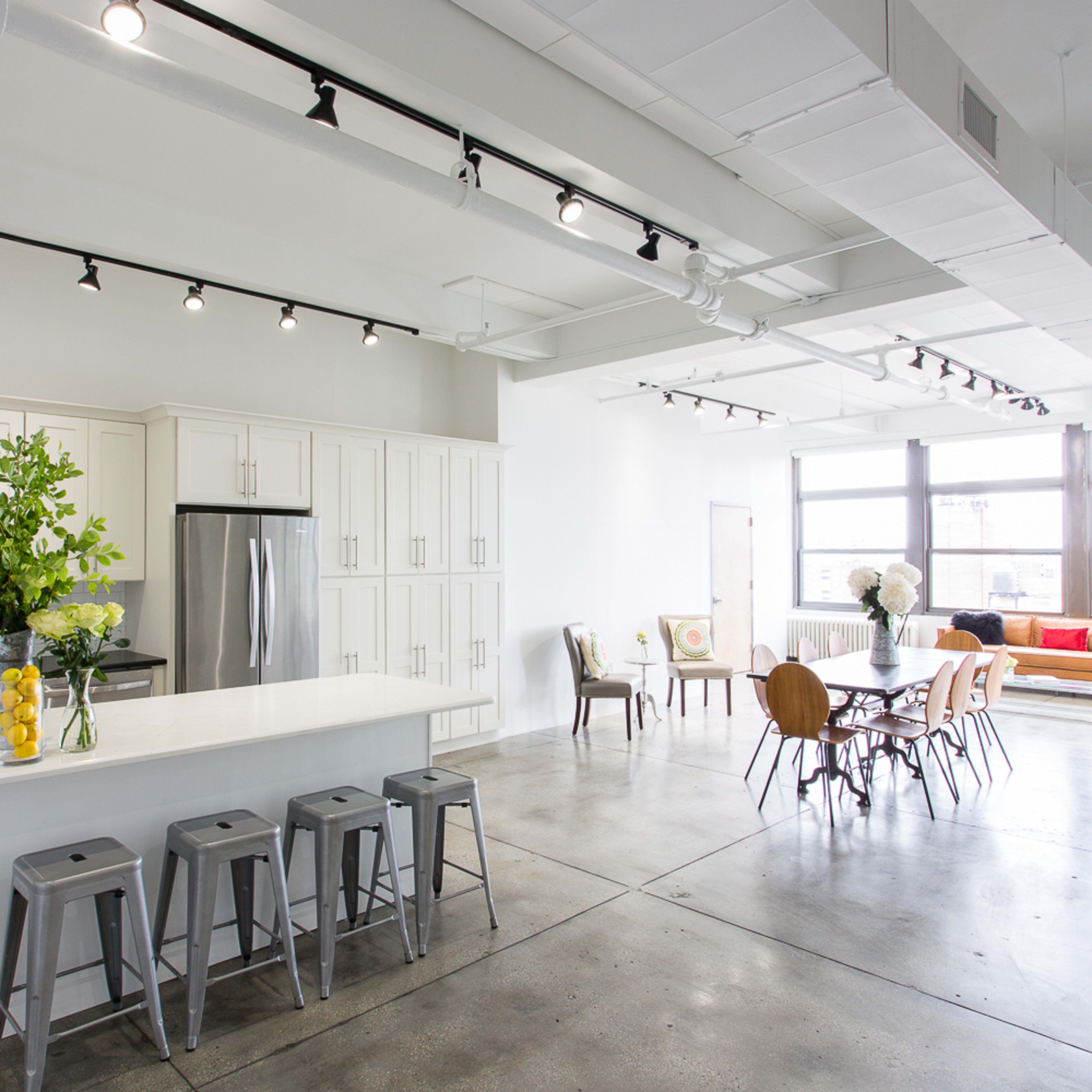 A modern, open-concept kitchen and dining area with white cabinetry, a large island, and an adjacent dining table surrounded by wooden chairs.