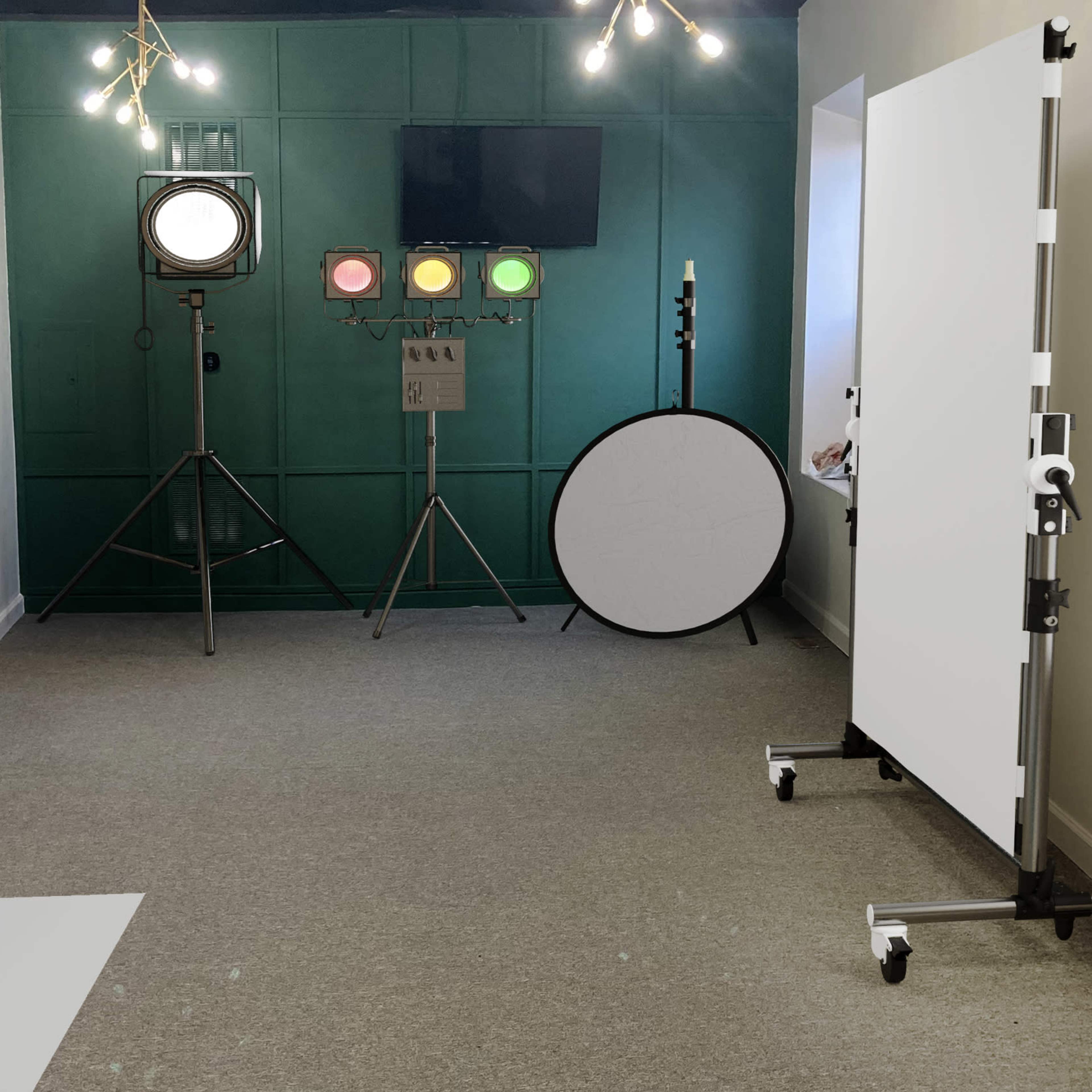 A photography studio with various lighting equipment, including softboxes and spotlights, set against a green wall.