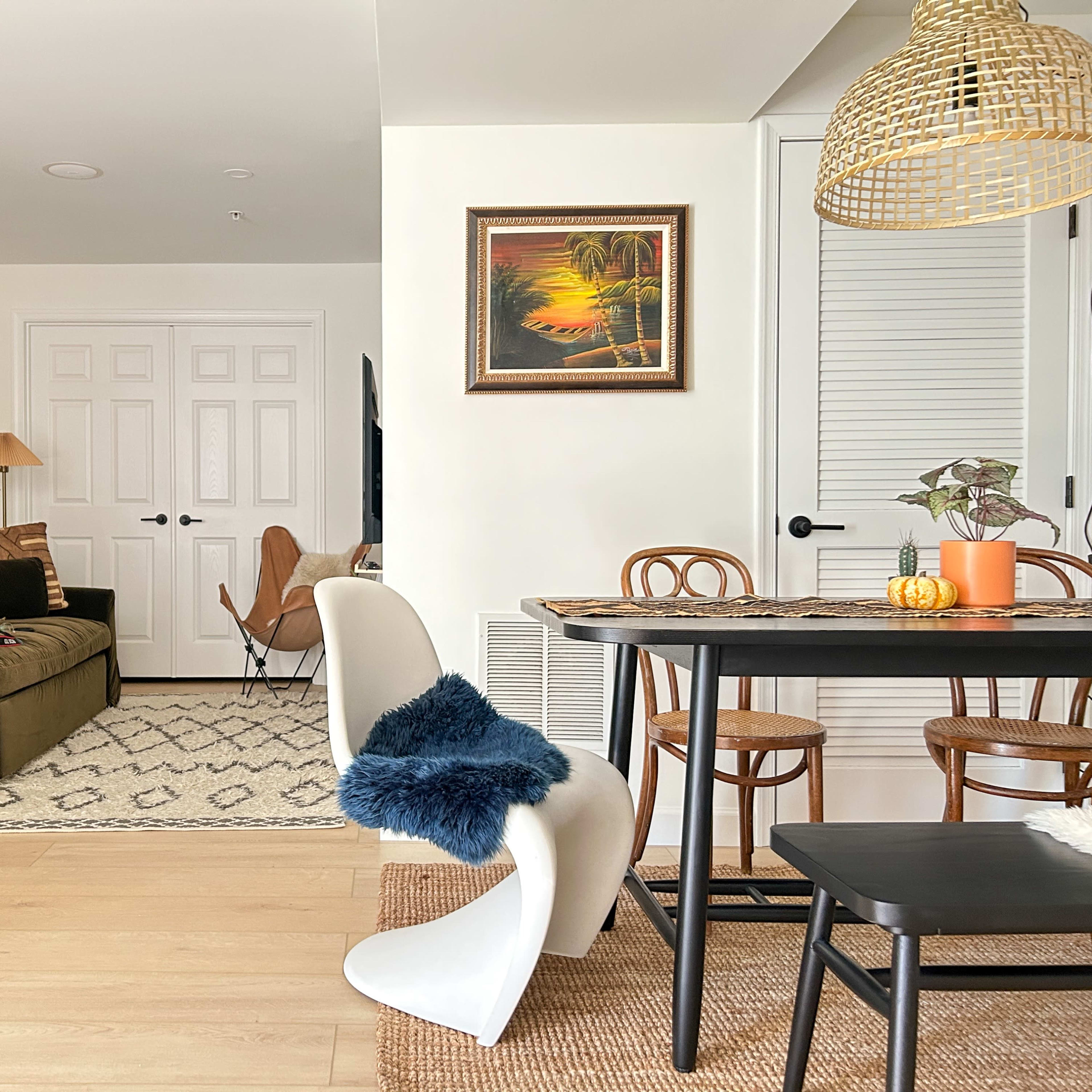 A modern living room and dining area featuring a sofa, a dining table with chairs, and decorative artwork on the walls.