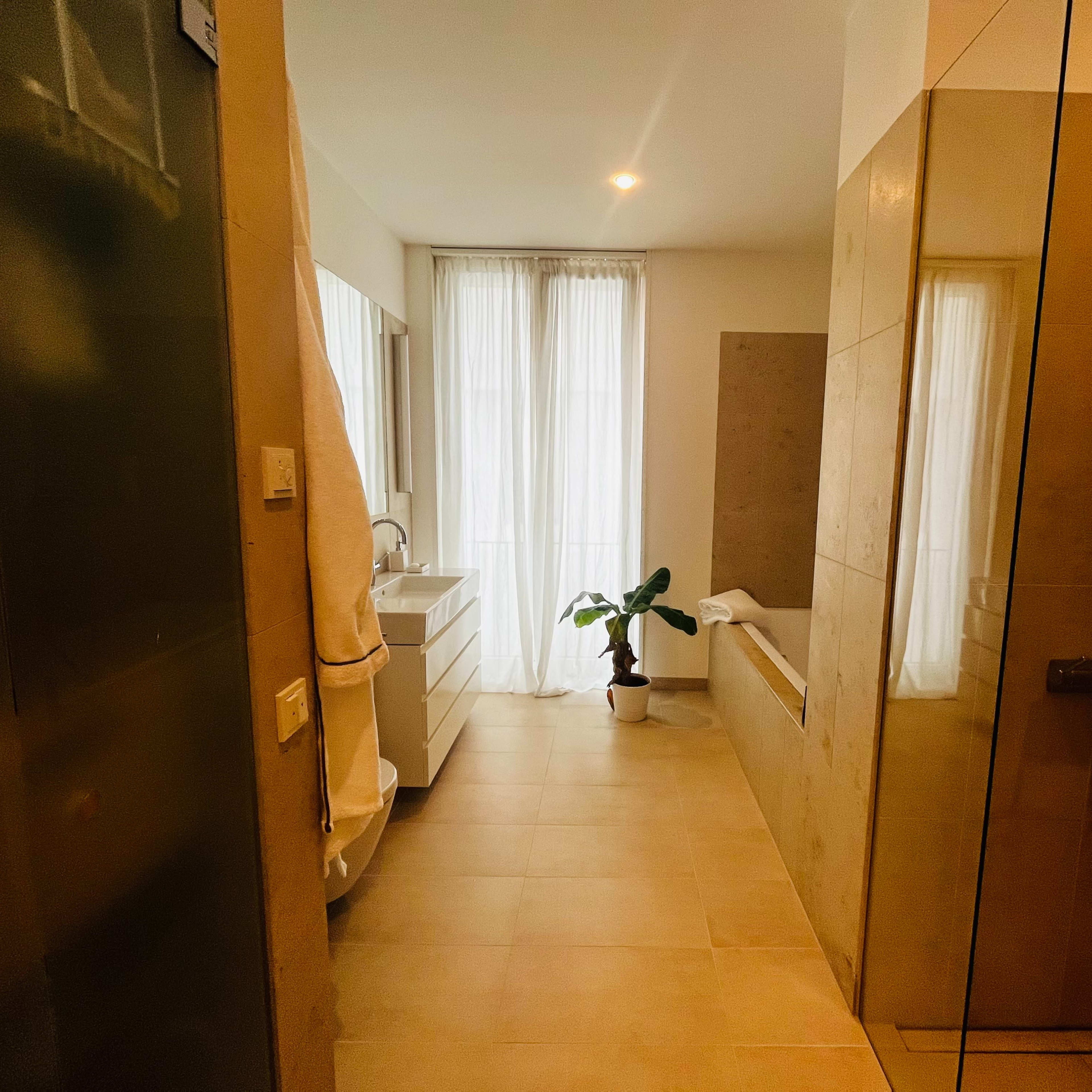 A modern bathroom featuring a glass shower, a bathtub, and large windows with natural light.