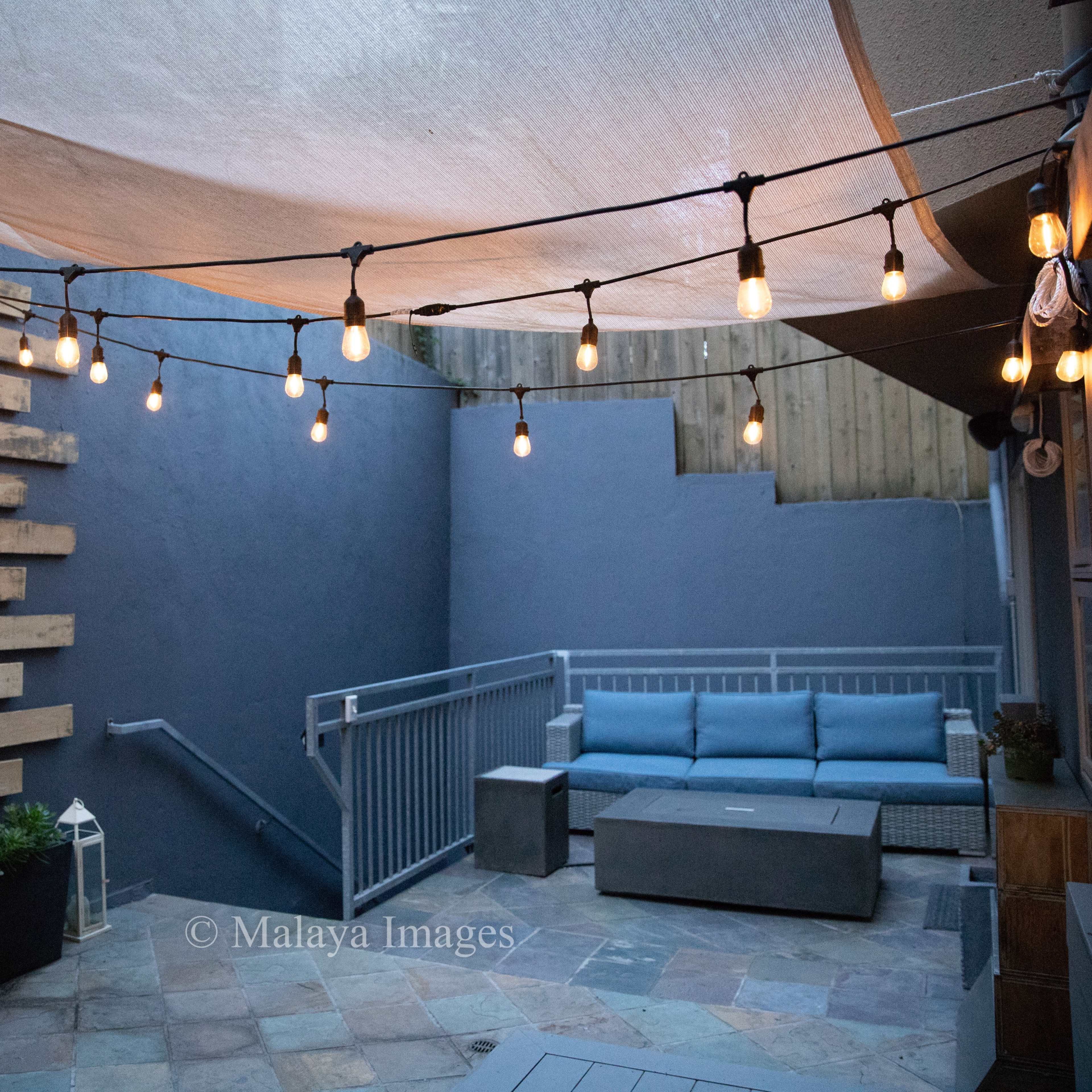 A cozy outdoor space with string lights, a seating area, and wooden wall accents.