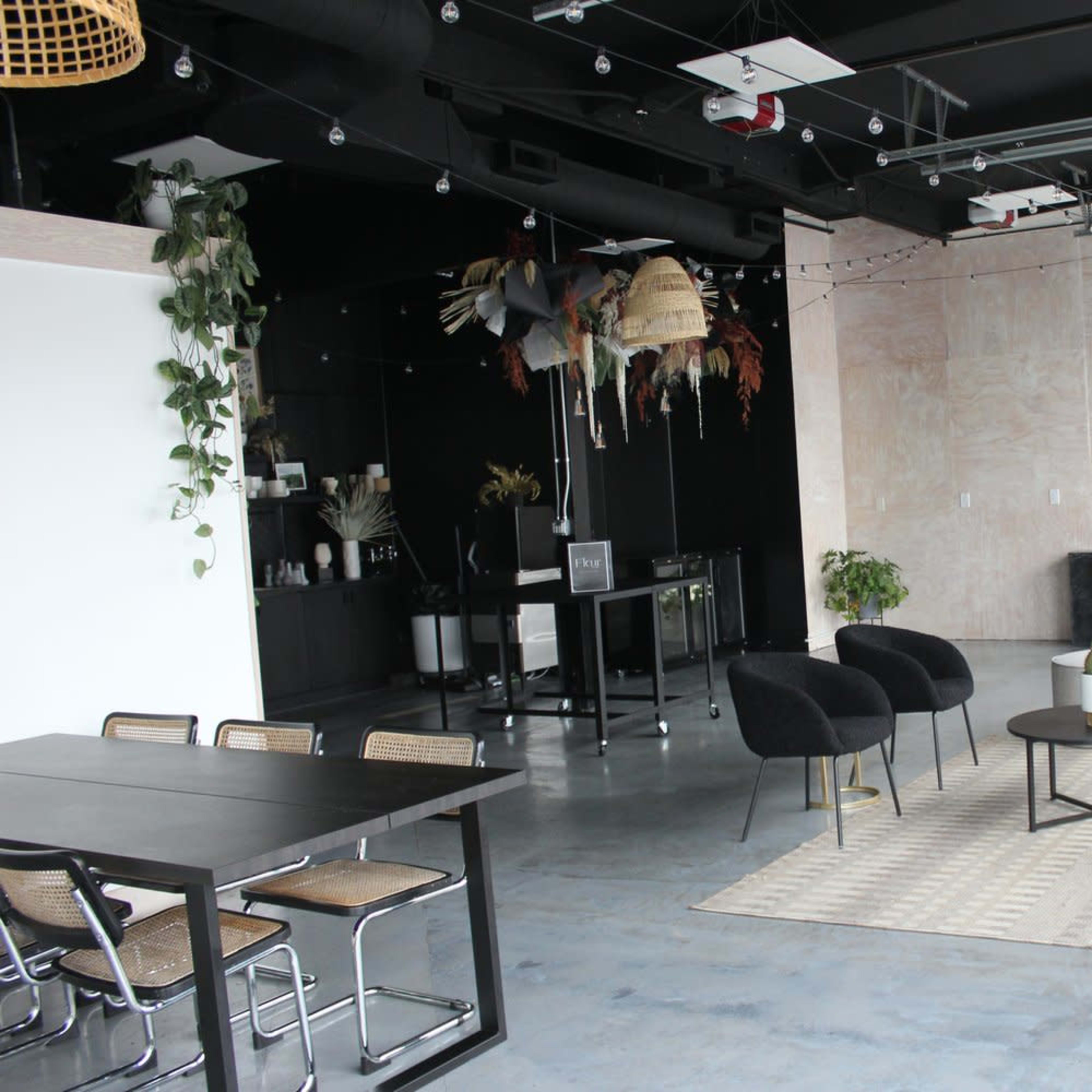 A modern interior space with a seating area featuring chairs and a table, alongside a kitchenette and decorative elements.