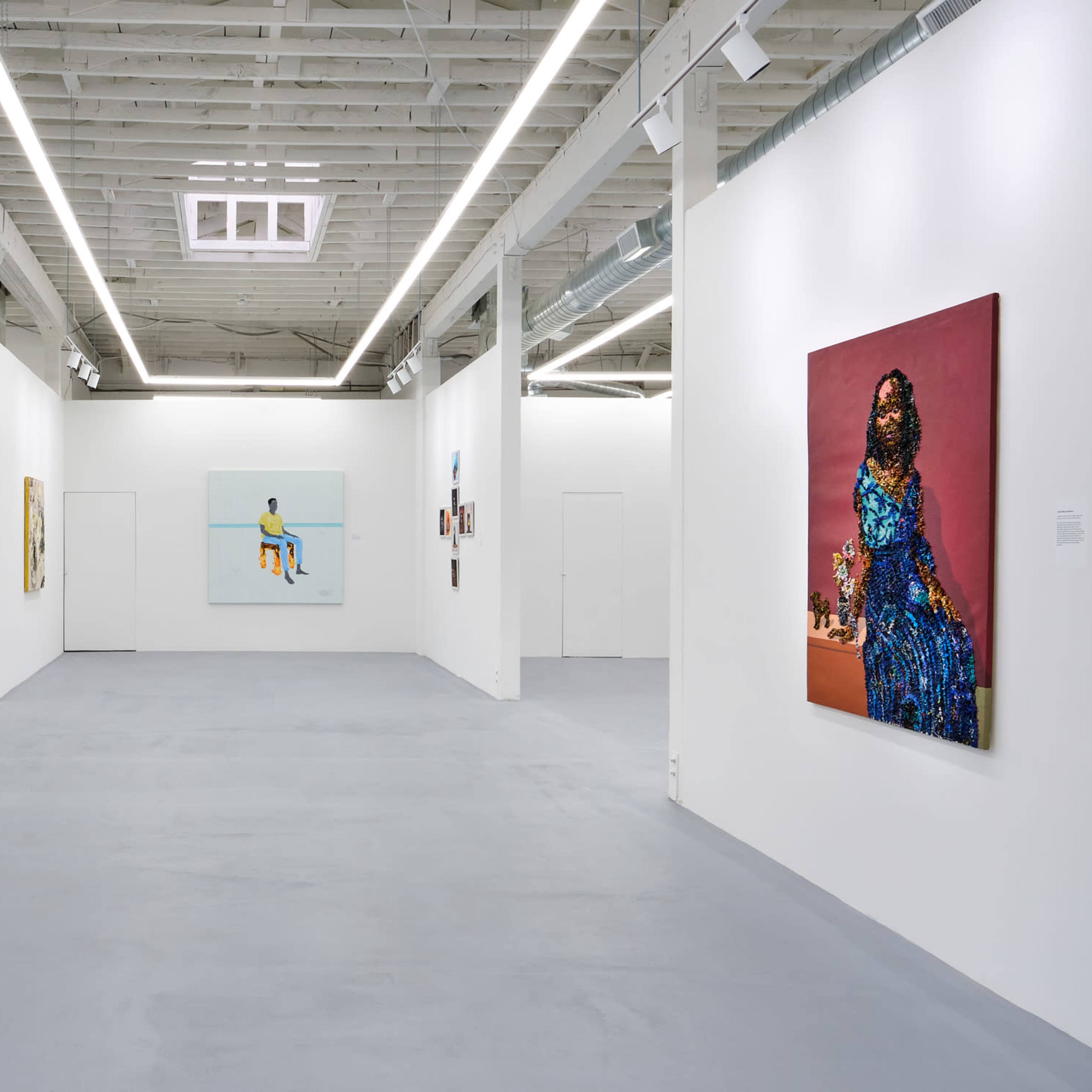 A modern art gallery showcasing several framed artworks on white walls with a gray floor.