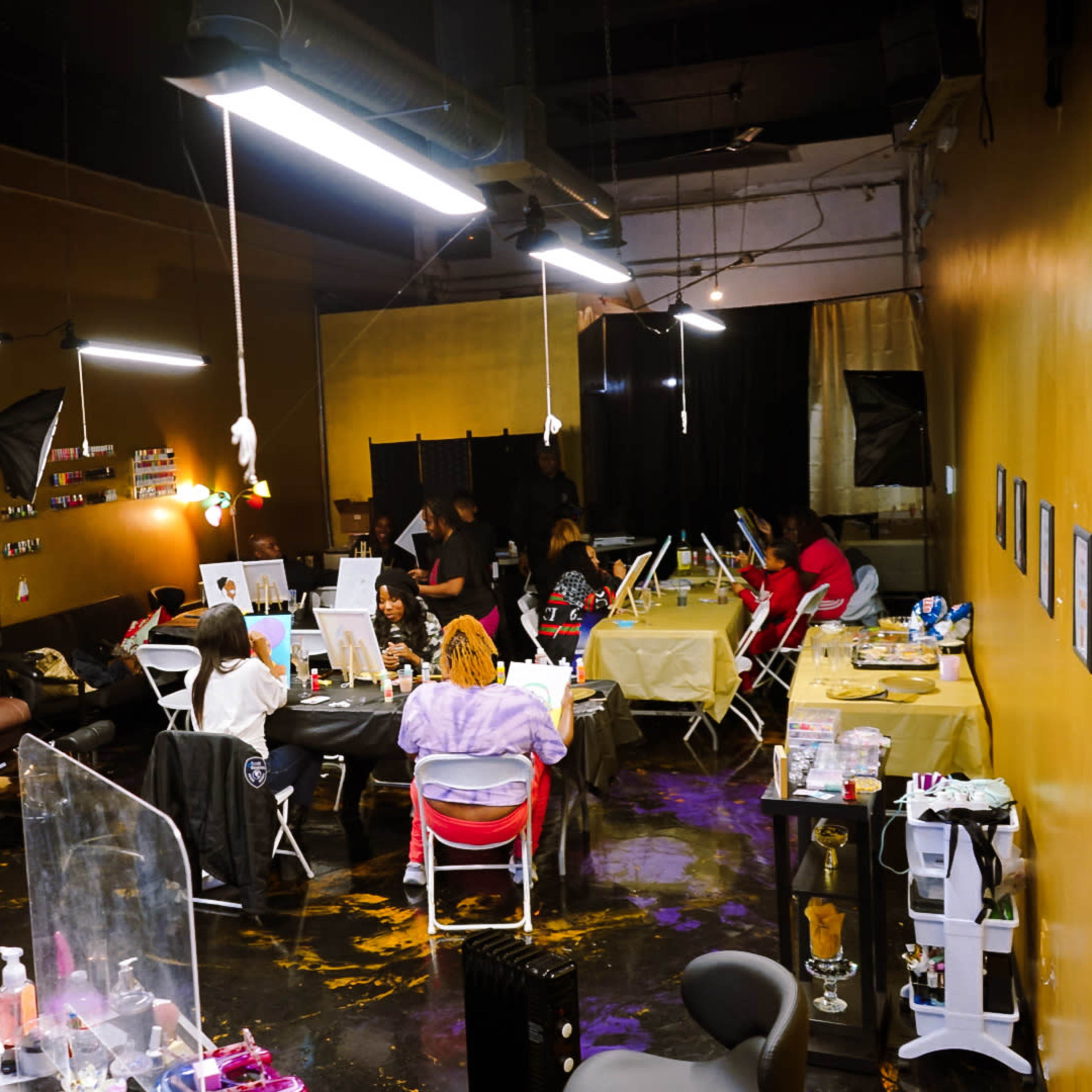 A beauty salon interior with multiple workstations, clients, and stylists engaged in various beauty treatments.