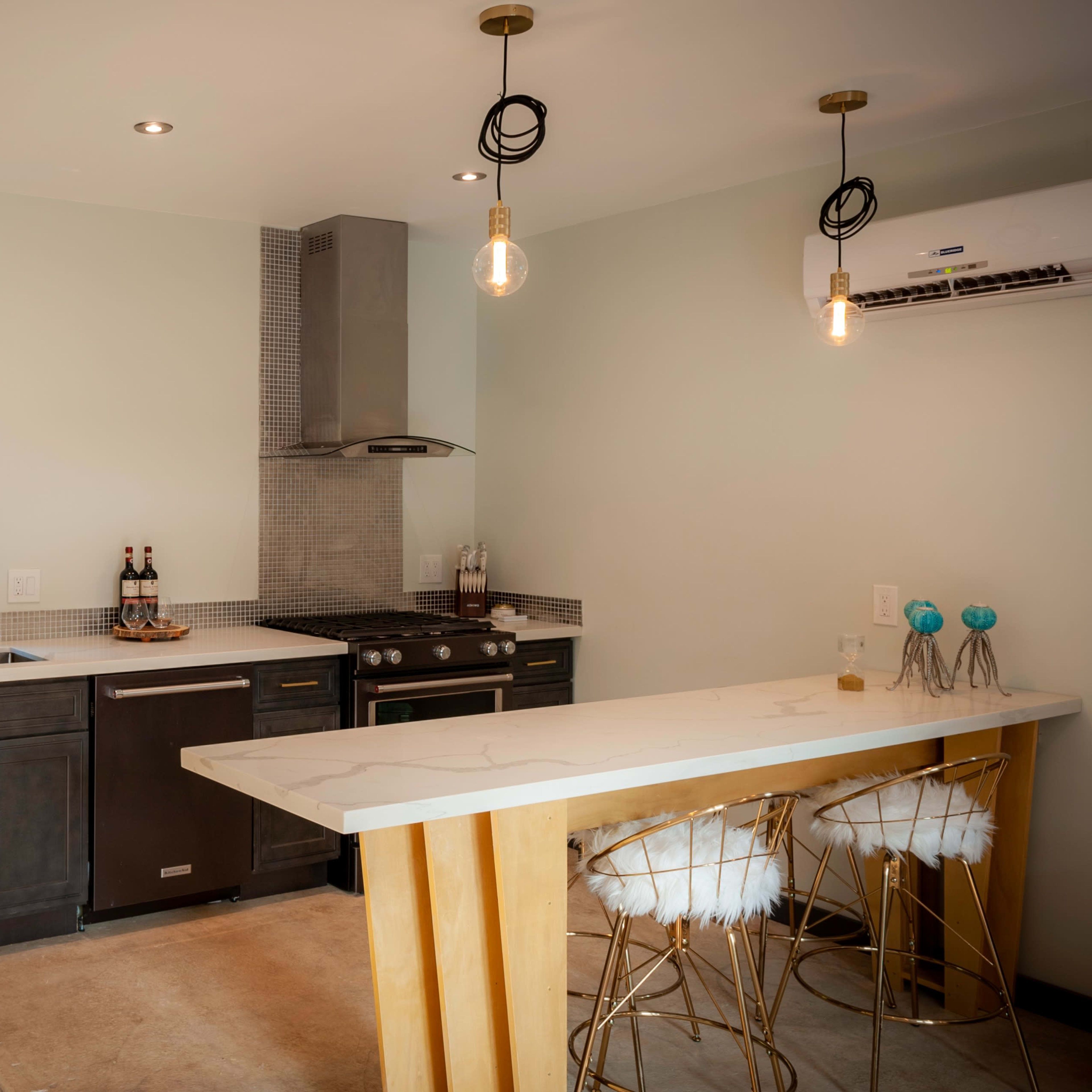 A modern kitchen with dark cabinetry, stainless steel appliances, and a countertop bar with stylish stools.