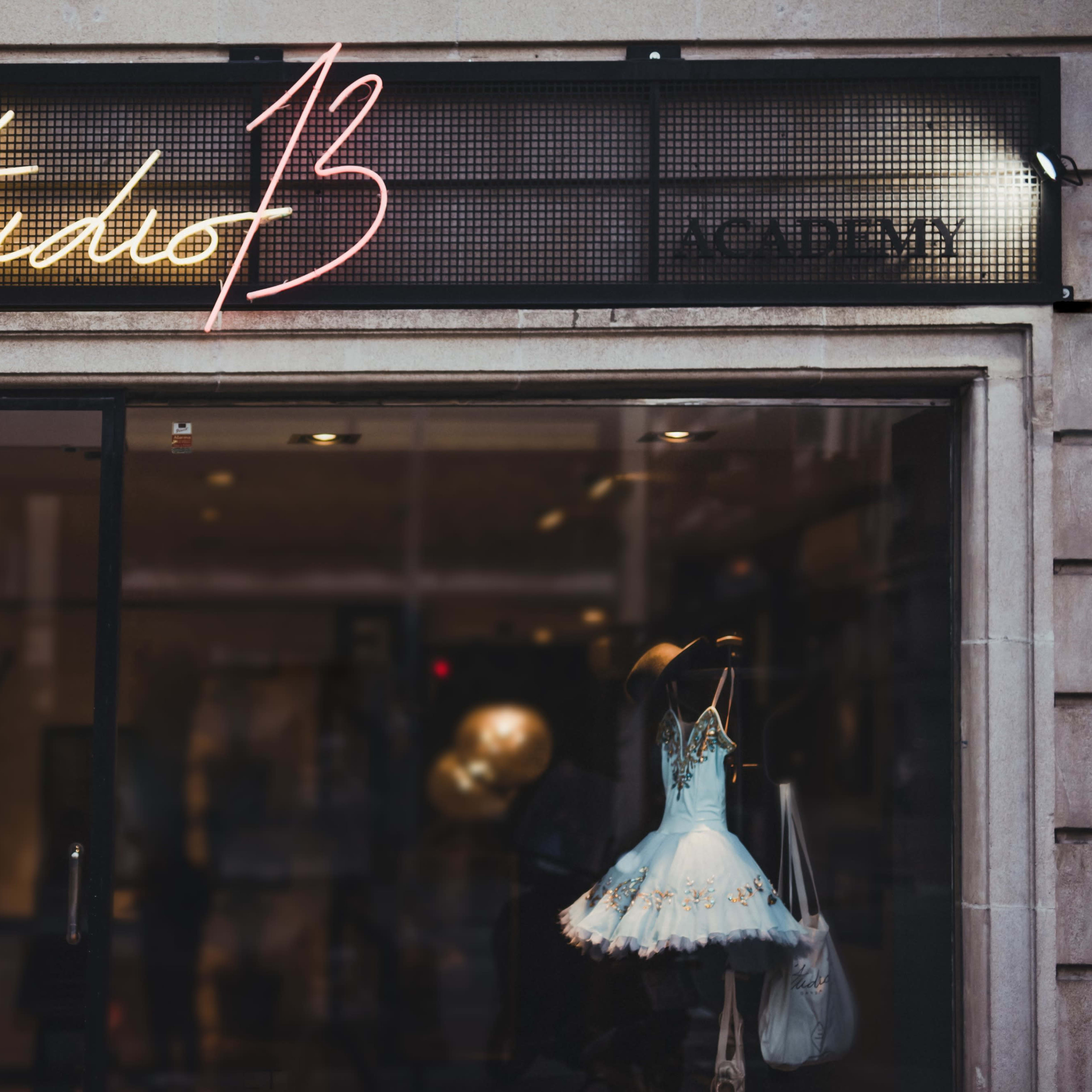 The storefront displays a neon sign reading "Studio 13" above a dress displayed in the window.