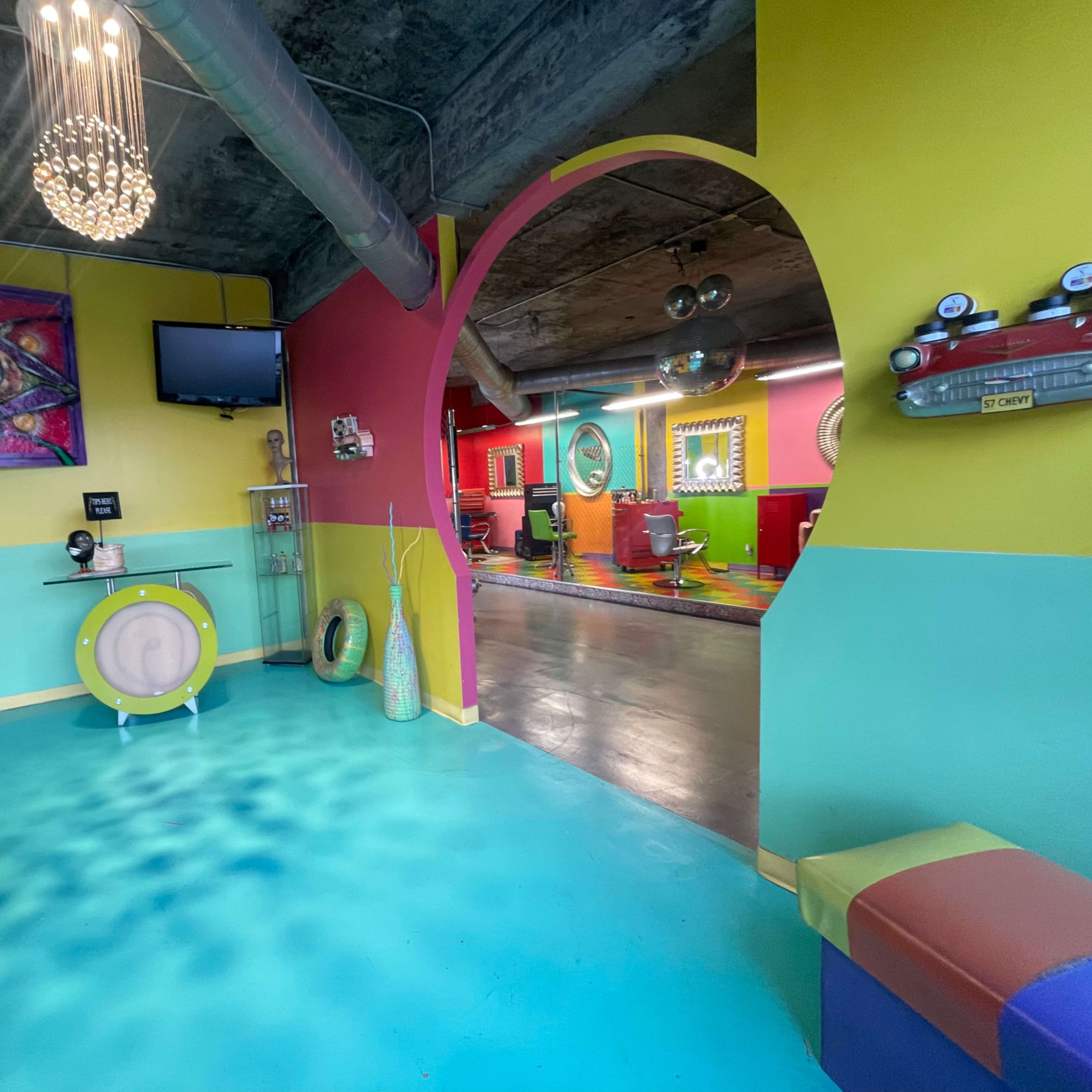 A colorful interior space featuring vibrant walls and unique furnishings, with a view into a room that appears to have a playful design.