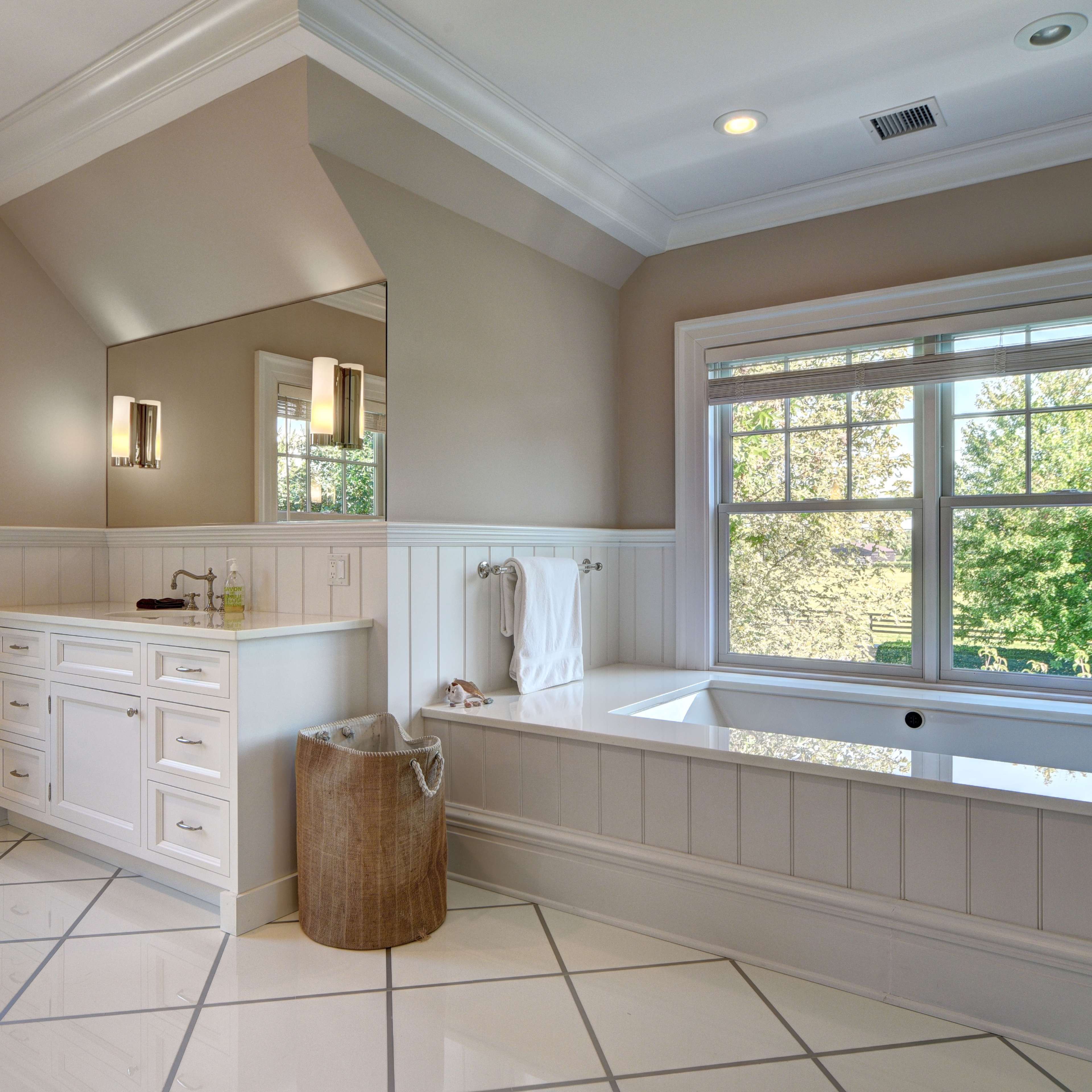 A spacious bathroom features a large bathtub, a double vanity with a mirror, and a window that provides natural light.