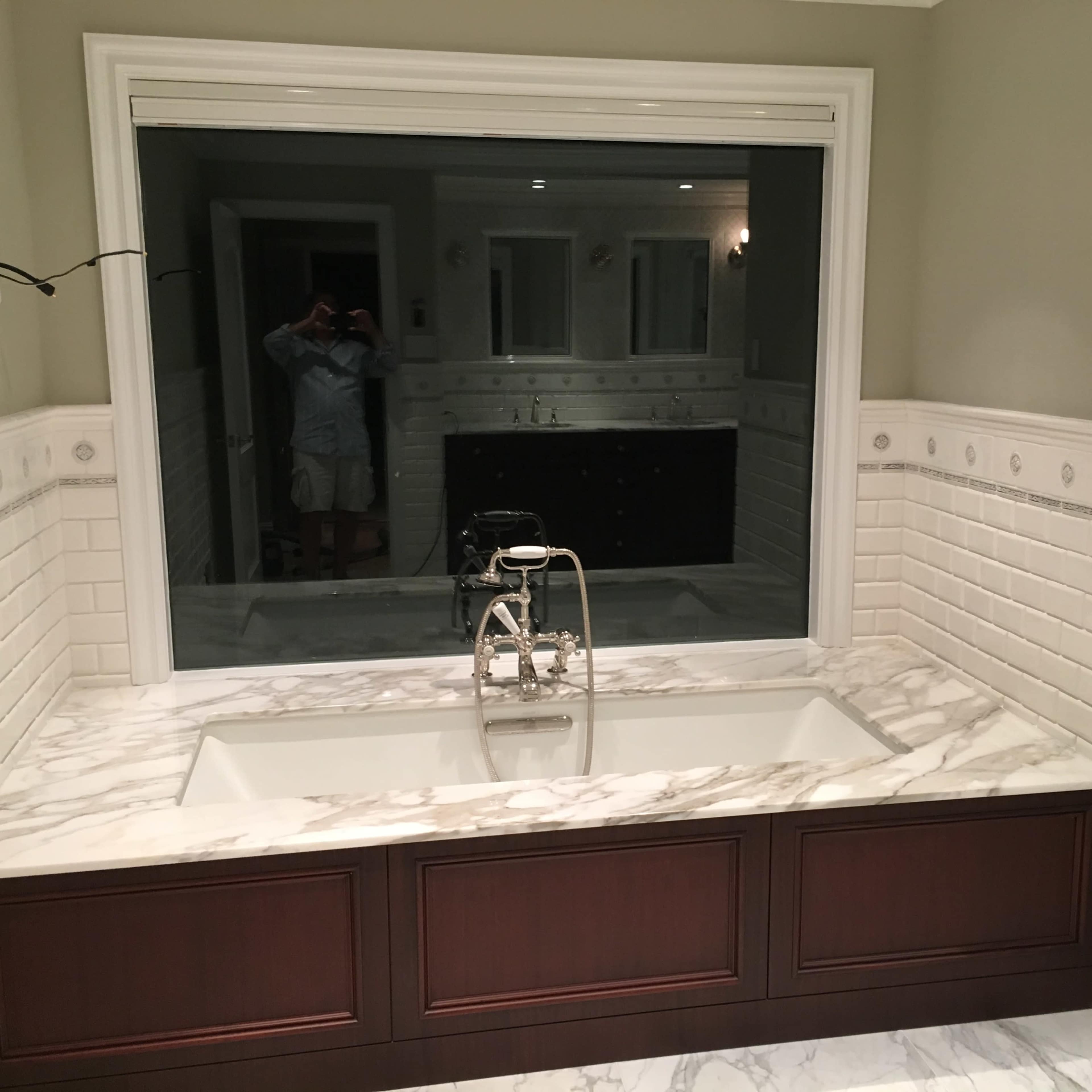 A spacious bathroom with a marble countertop, a modern sink fixture, and tiled walls.