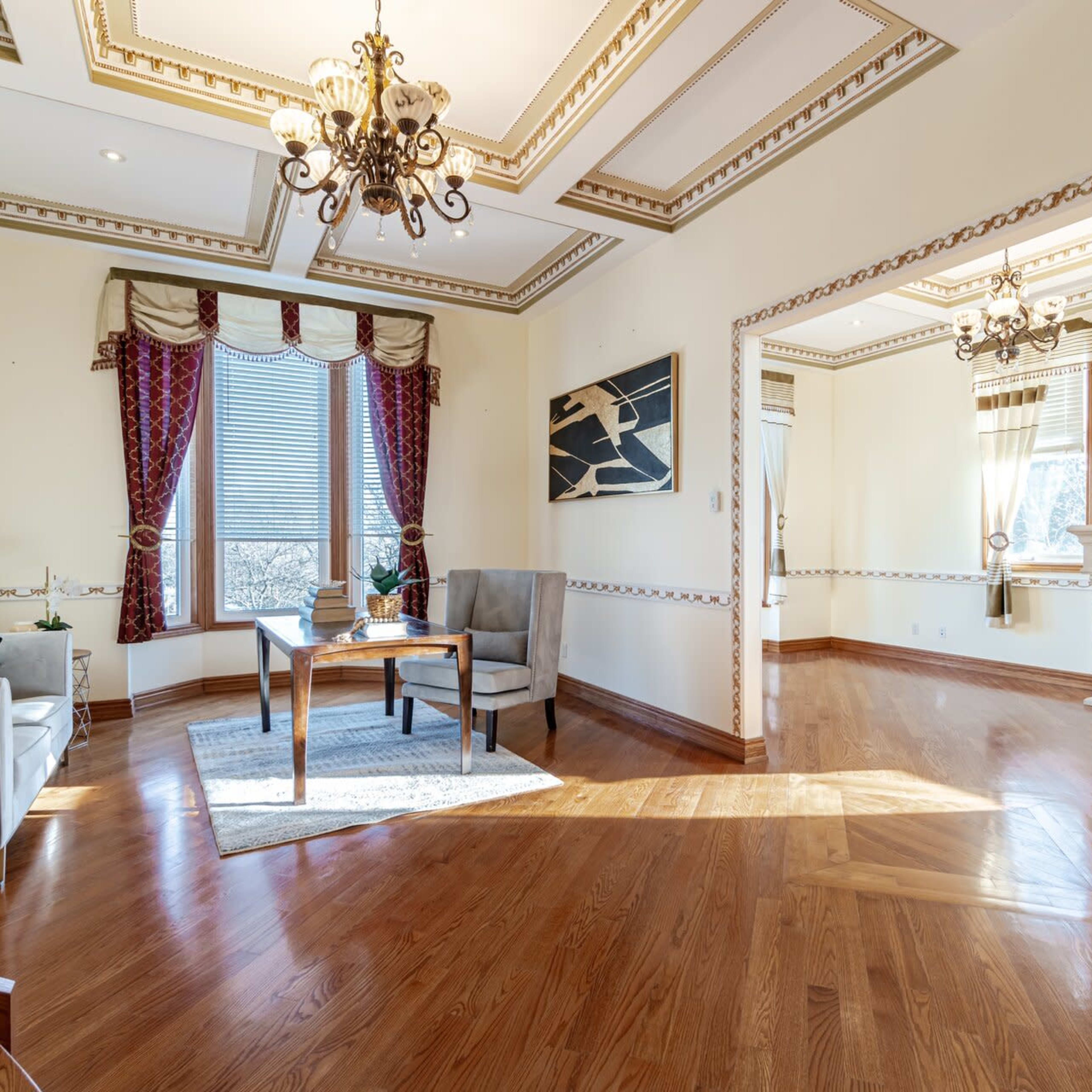 A spacious living room featuring a fireplace, large windows, classical decor, and elegant furniture.