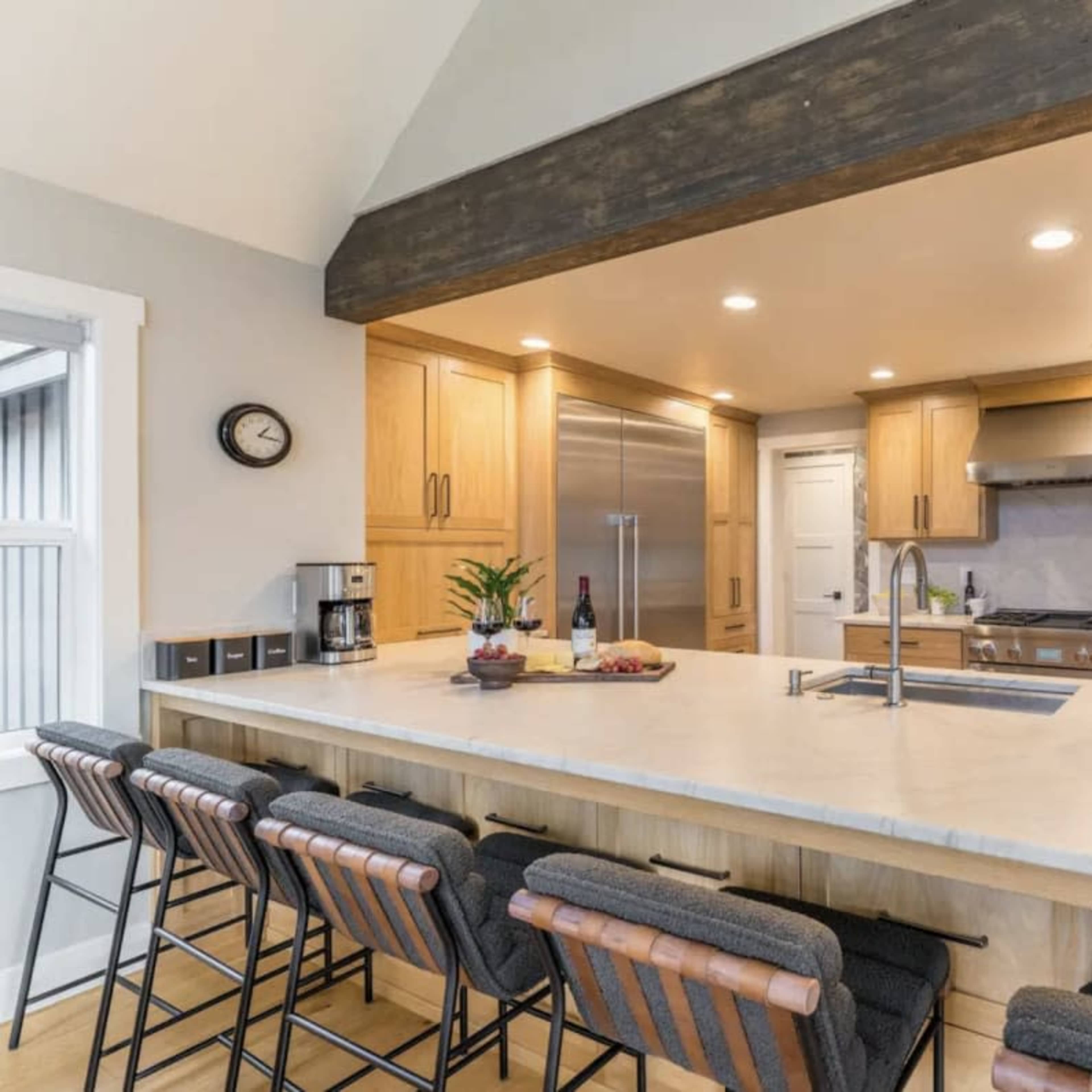 A modern kitchen featuring wooden cabinetry, a large island with seating, and stainless steel appliances.