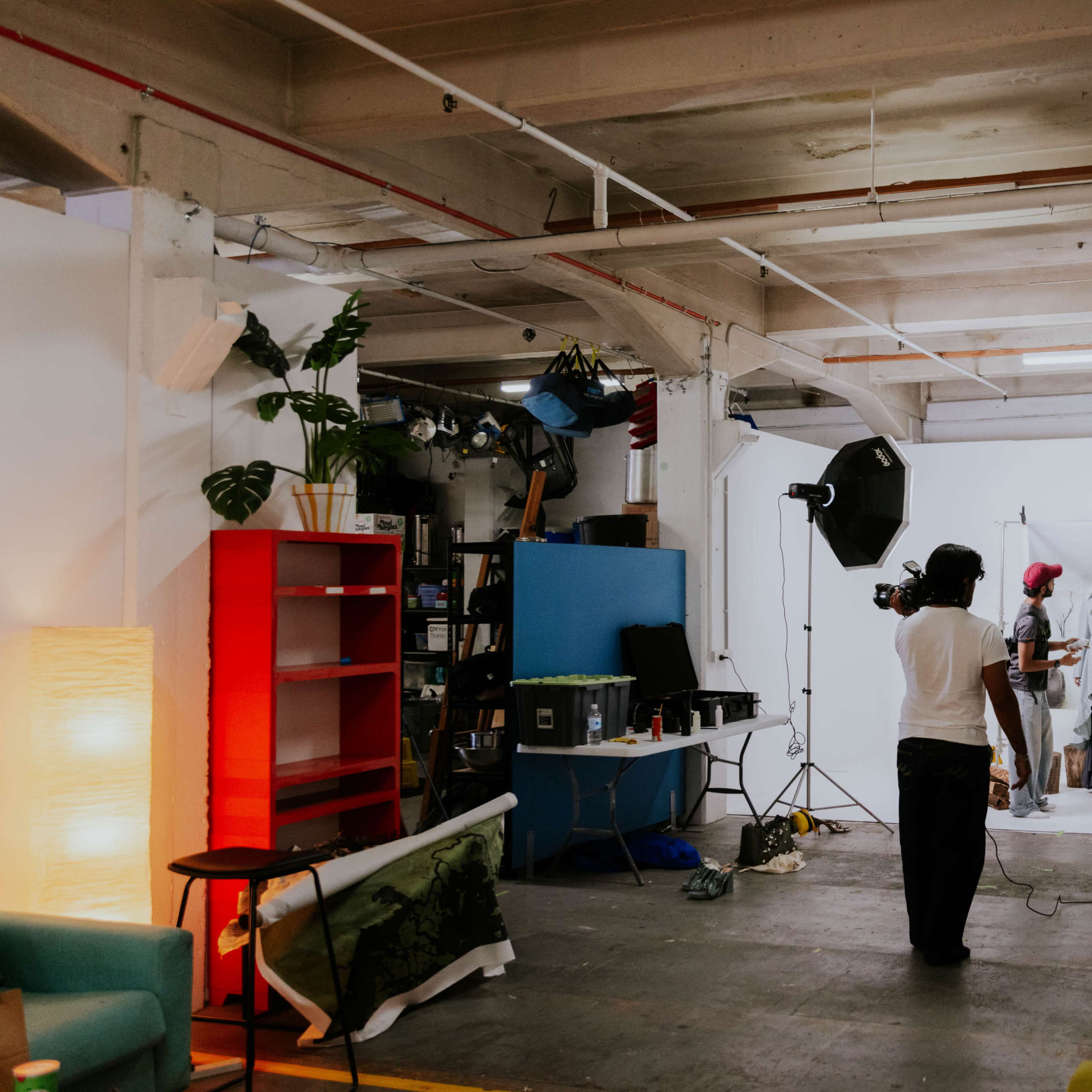 A photography studio setup features a team capturing images of a model against a white backdrop, with lighting equipment in use.