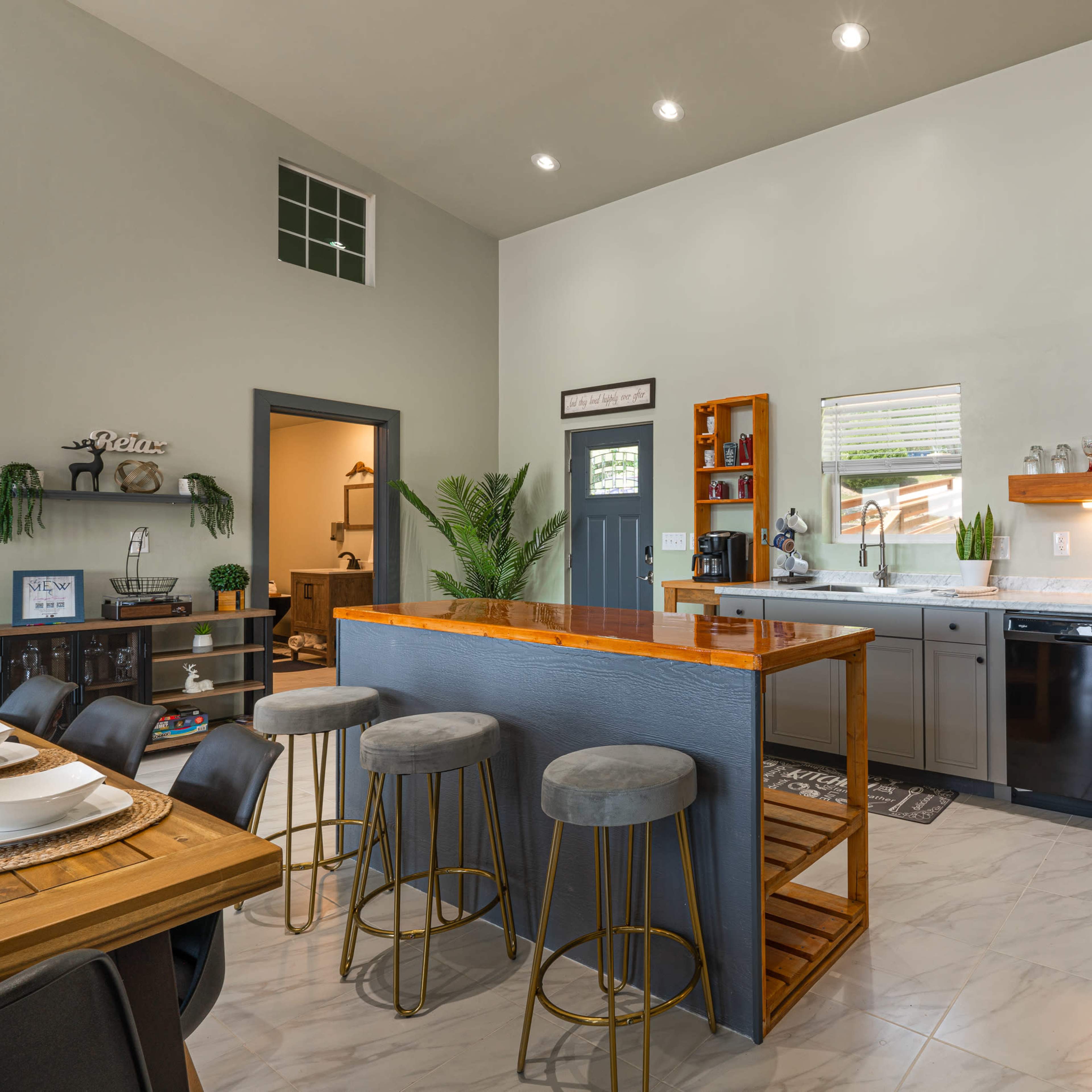 A modern kitchen with gray cabinetry, a large island with bar seating, and stainless steel appliances.