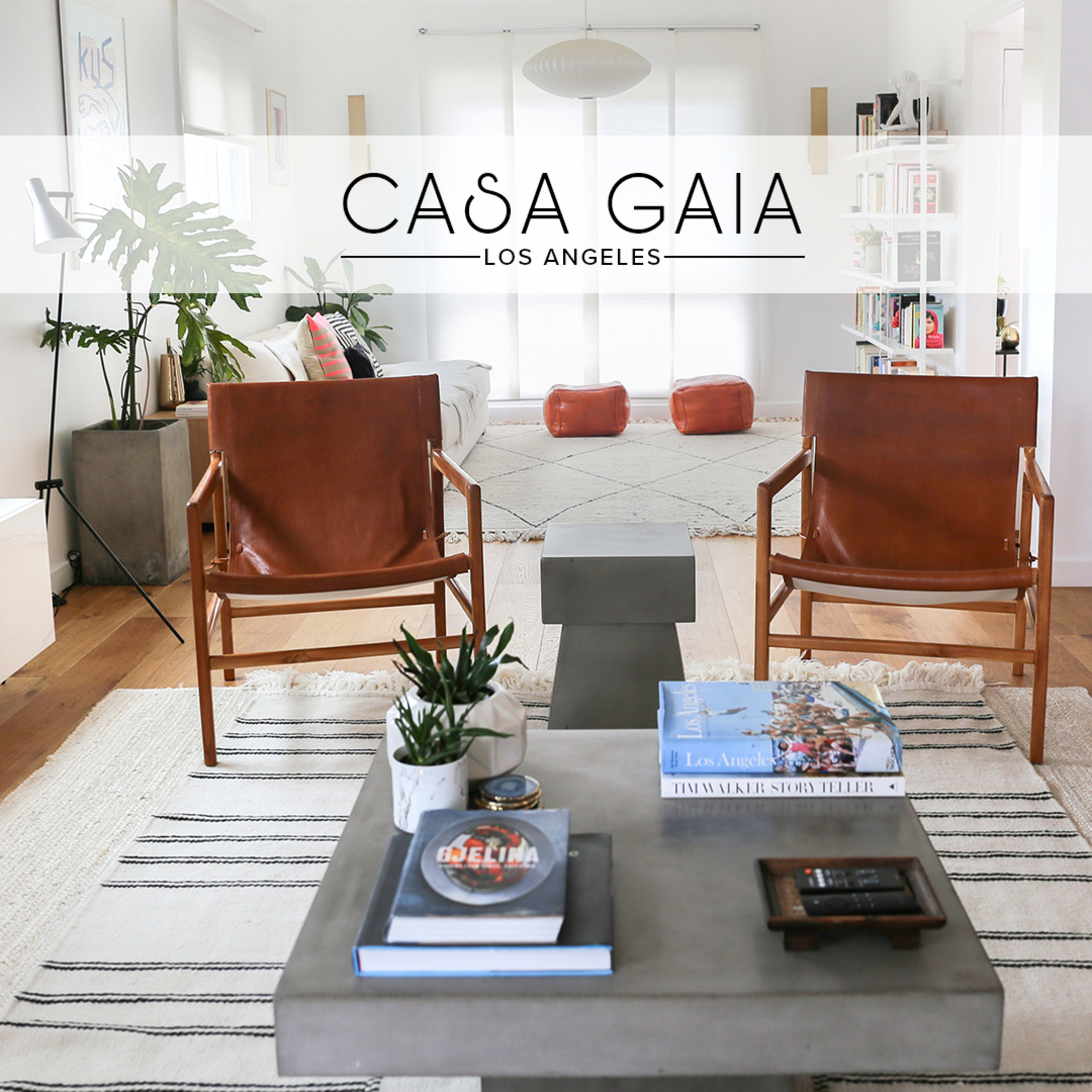 A modern living room featuring two leather chairs, a concrete coffee table, and light wood flooring with a rug.