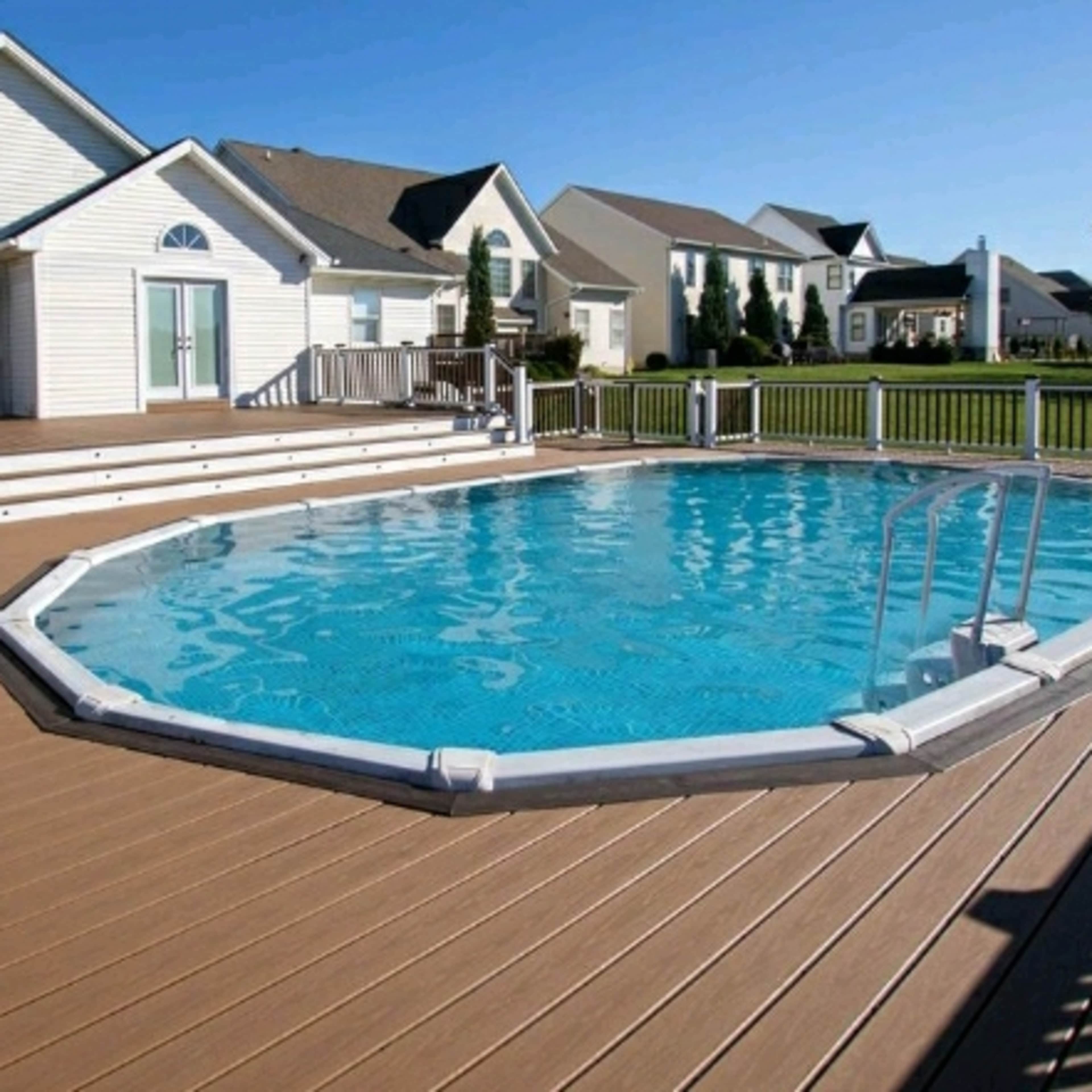 An octagonal swimming pool surrounded by a wooden deck and a house in the background.