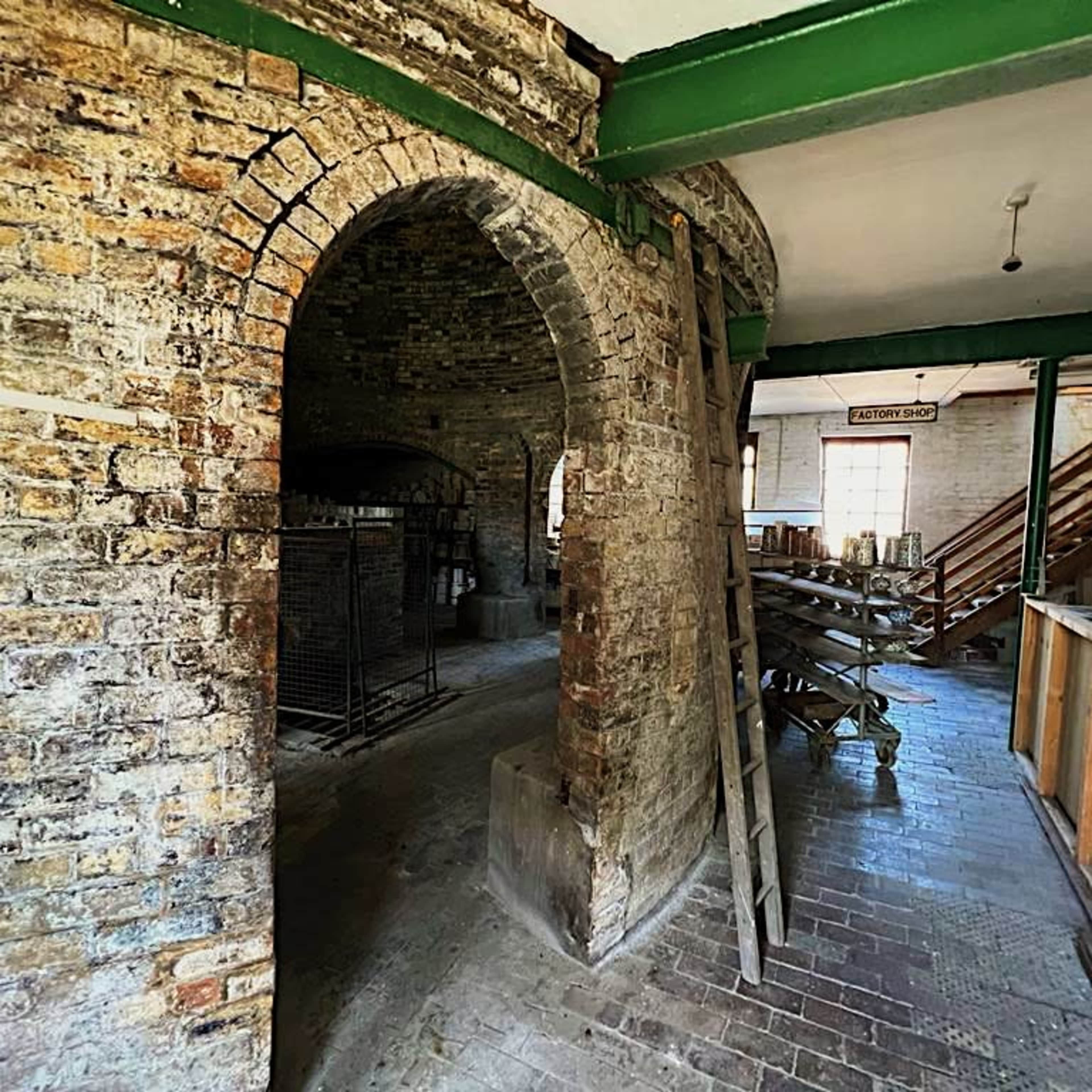 An interior space with exposed brick walls, arched doorways, and wooden scaffolding.