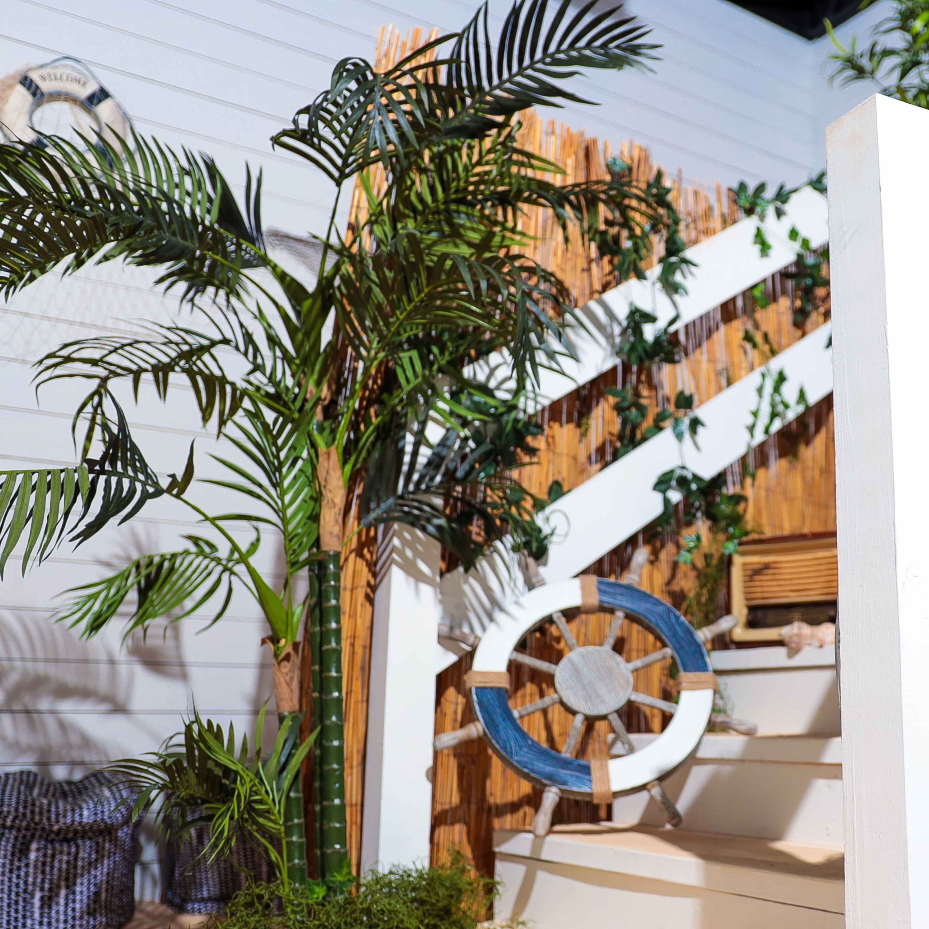A staircase is adorned with a wooden railing, decorative plants, a life preserver, and nautical-themed decor.