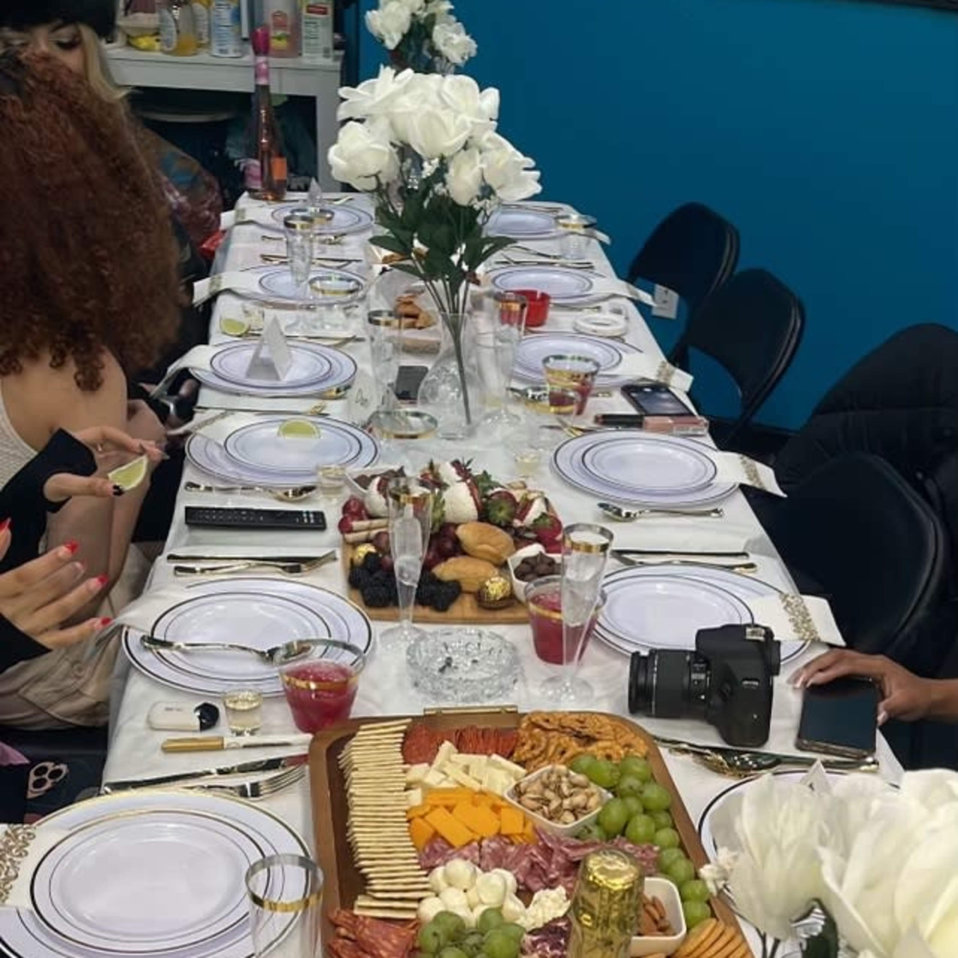 A long dinner table elegantly set with white plates, a variety of food platters, and decorative flowers, ready for a gathering.