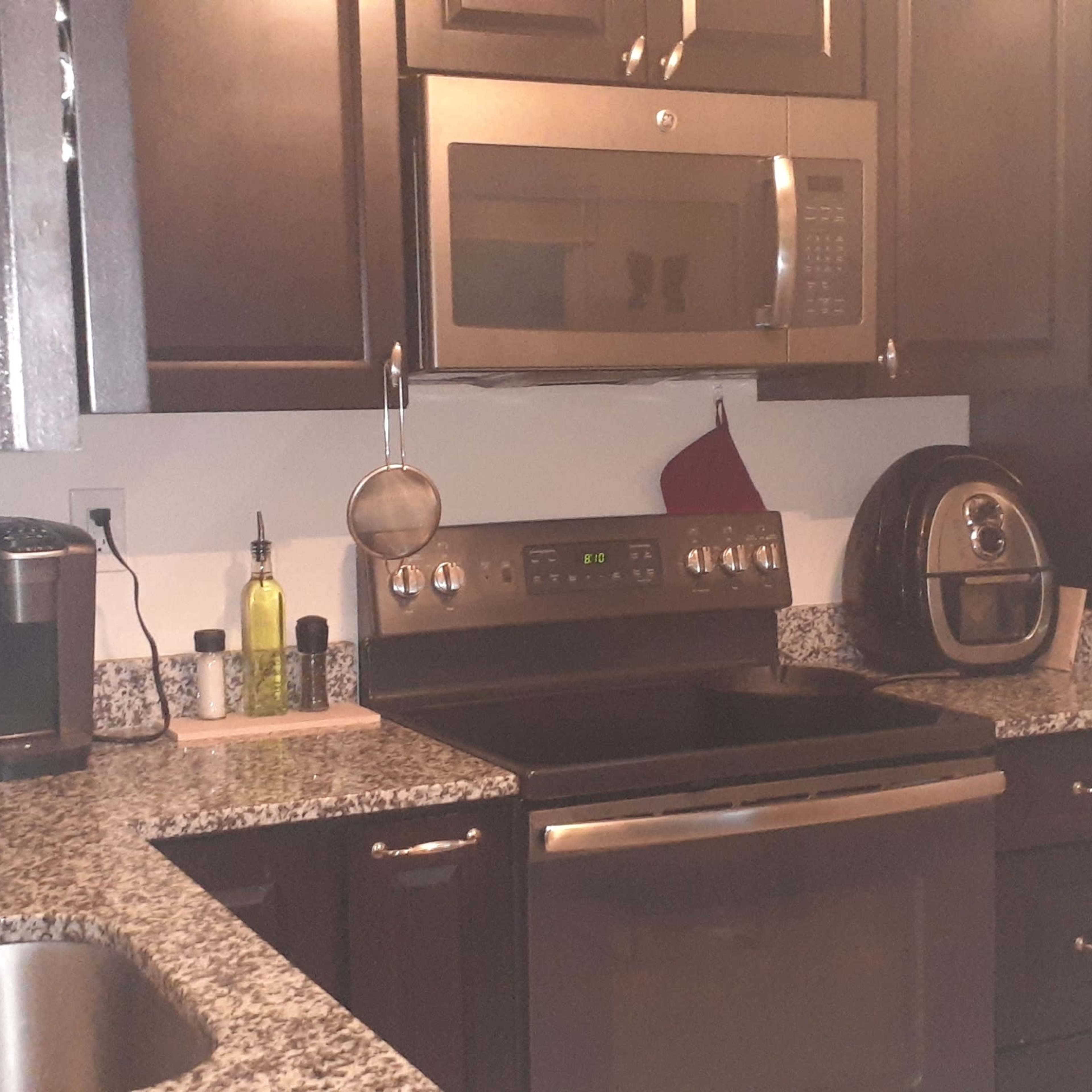 The kitchen features dark cabinets, stainless steel appliances, and a countertop with a sink and various kitchen tools.