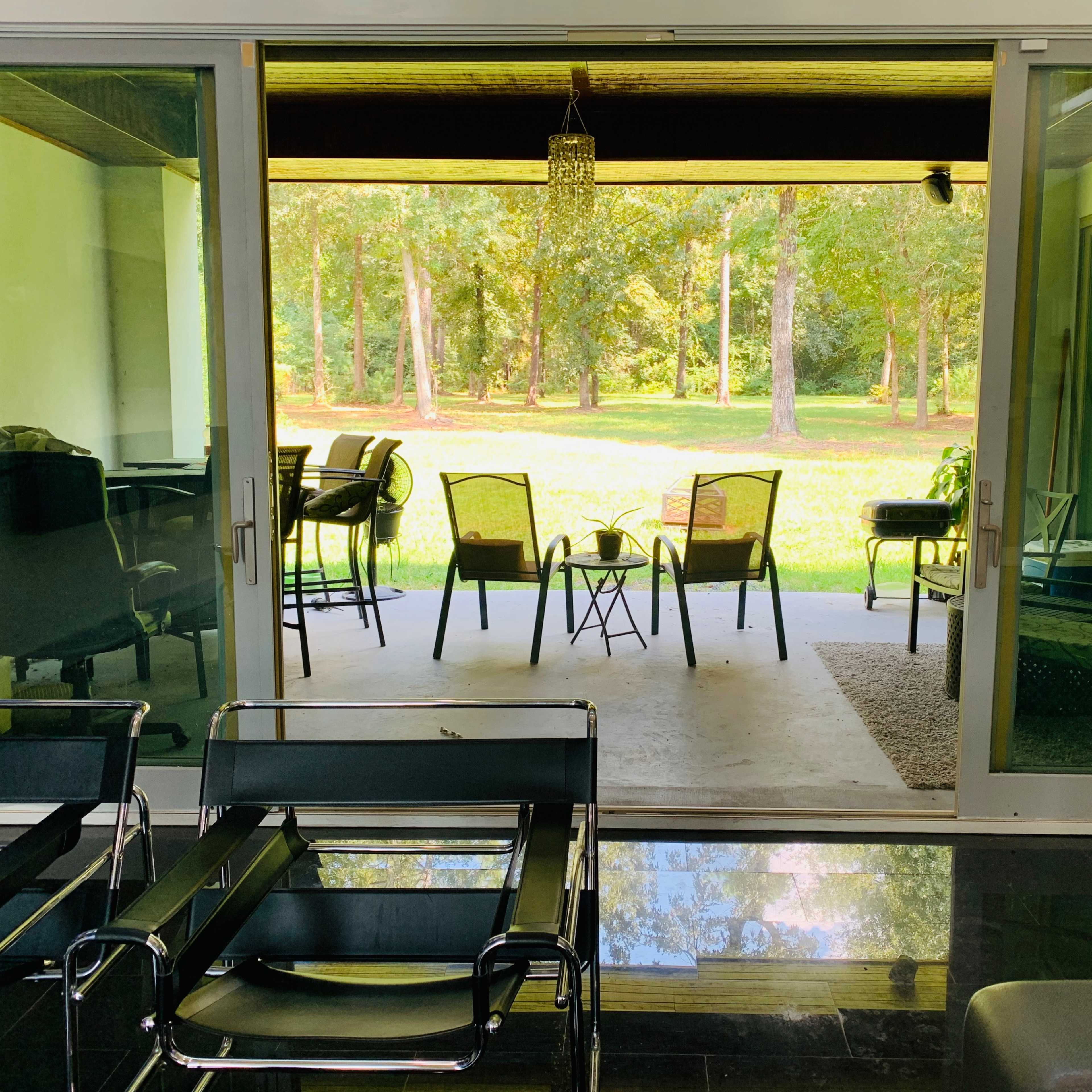 A modern room with glass doors leading to a patio overlooking a grassy area and trees.