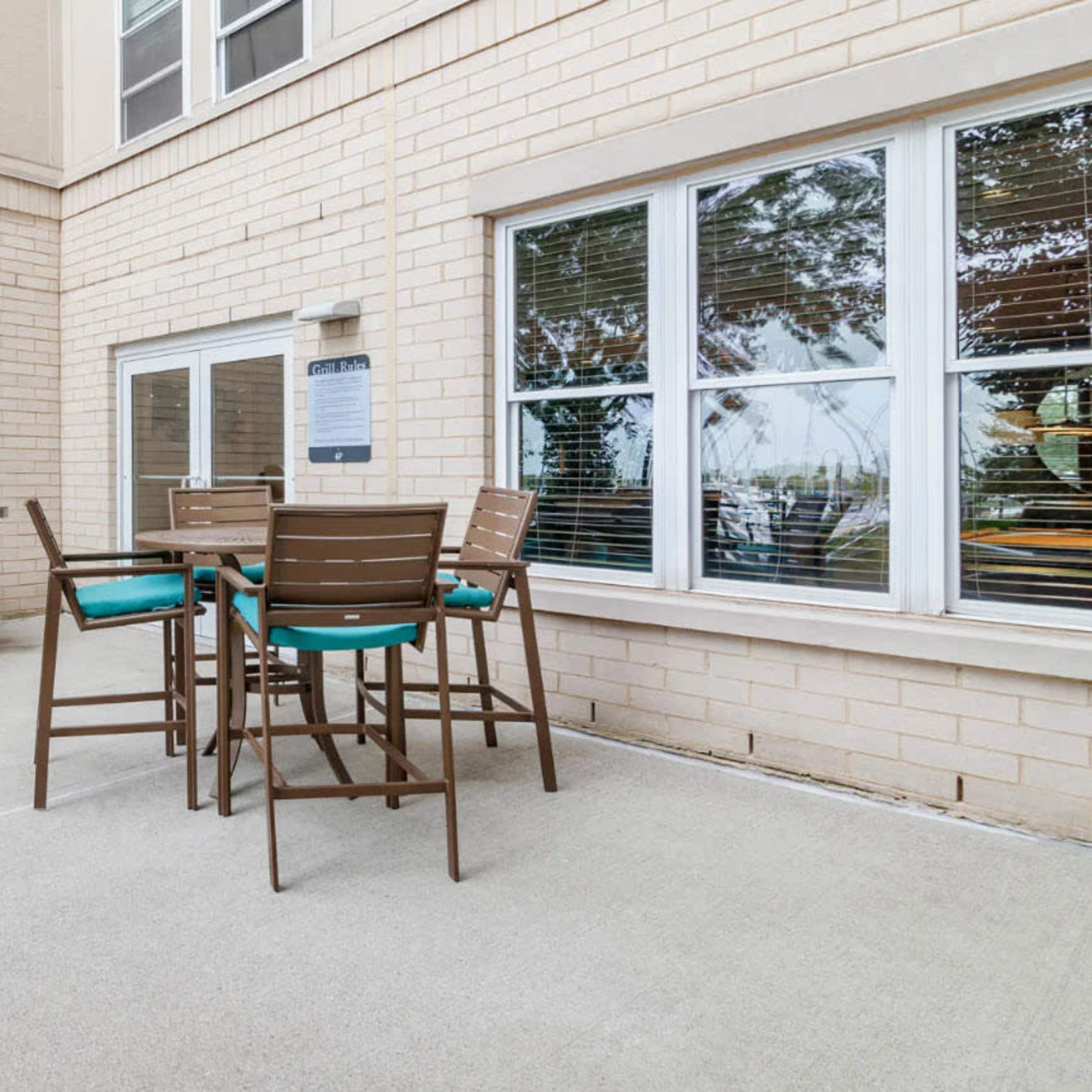 A patio area featuring two gas grills and a dining set with high chairs.