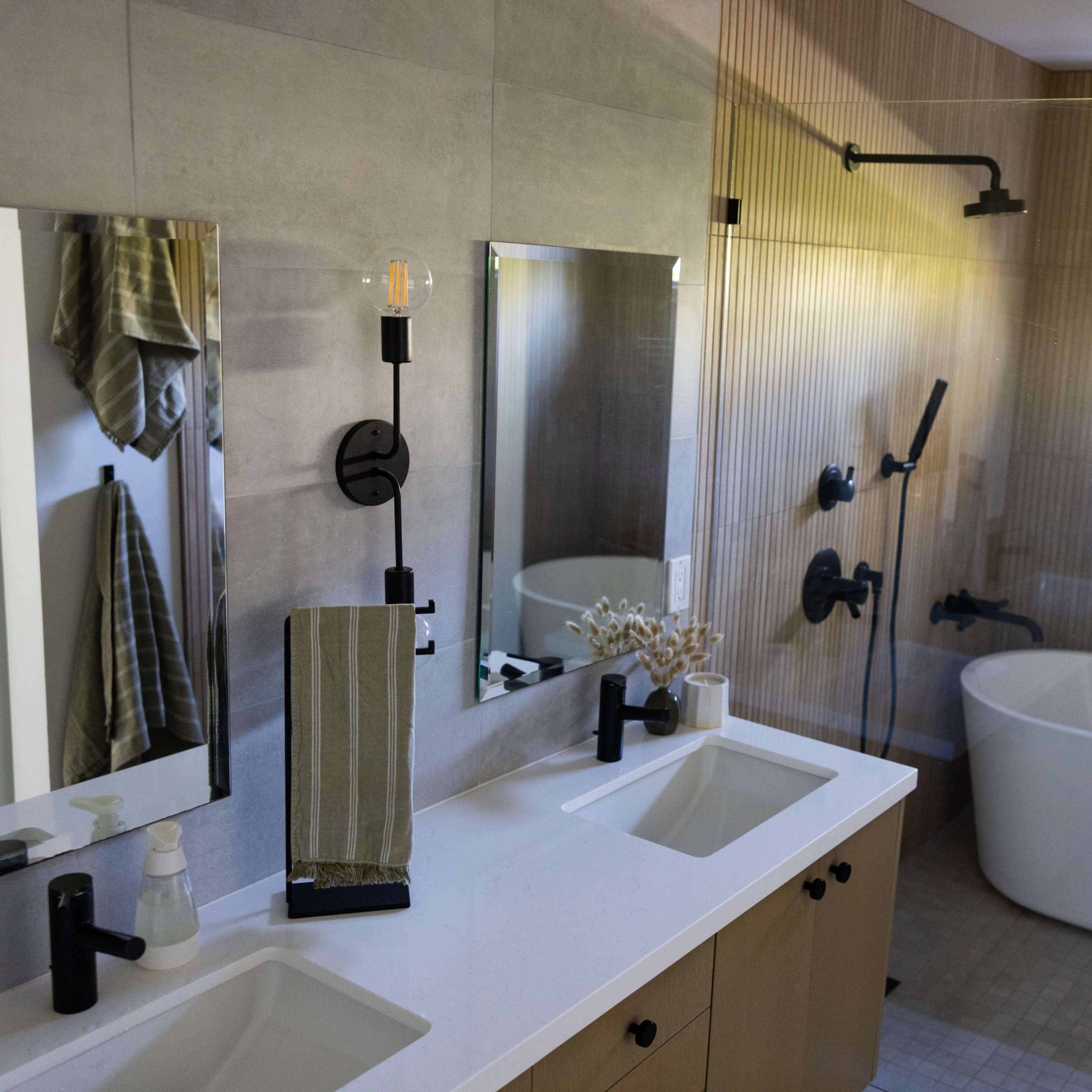 A modern bathroom features a freestanding bathtub, dual sinks with mirrors, and a walk-in shower with a glass partition.