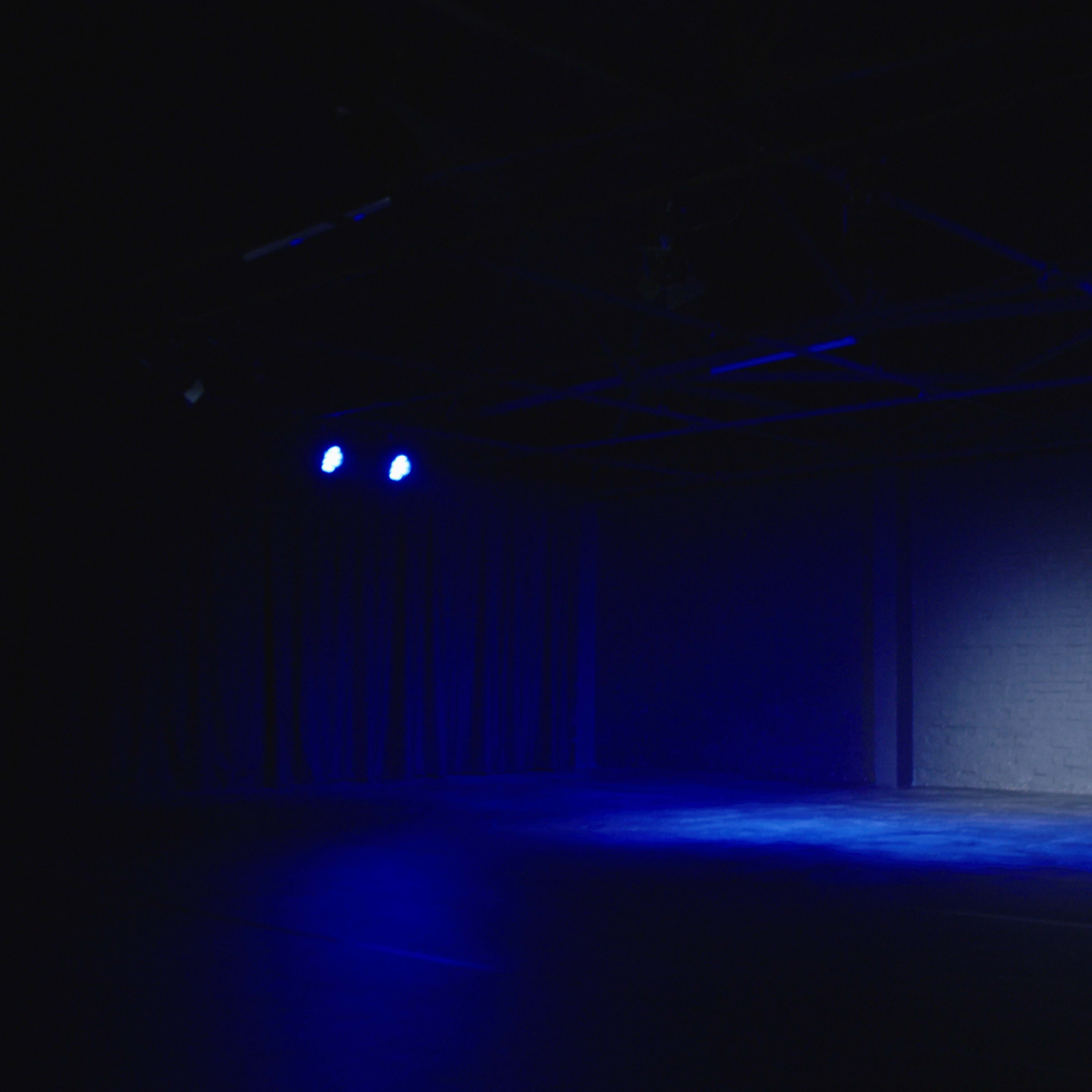 An empty stage illuminated by blue lights against a dark backdrop.