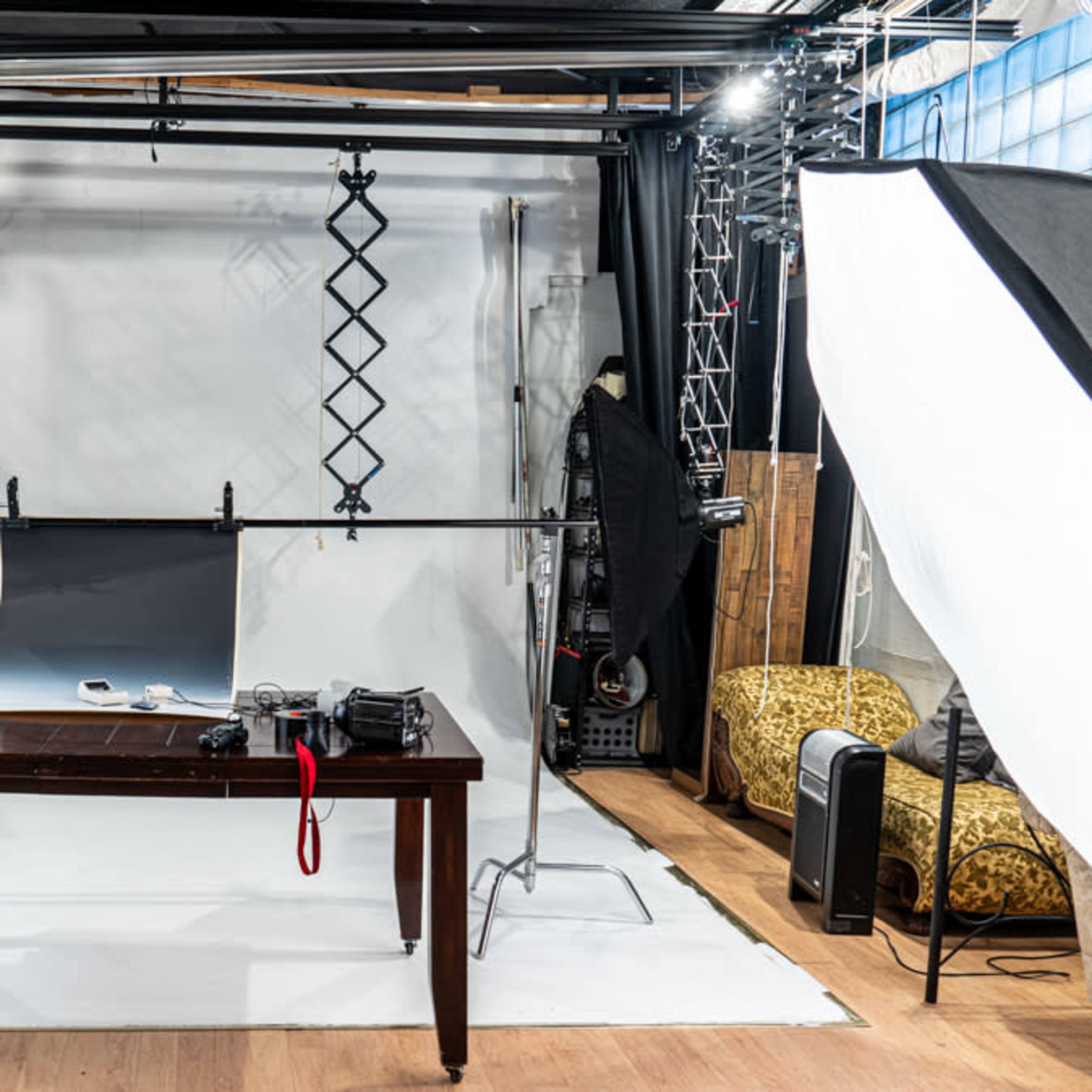 A photography studio equipped with a wooden table, lighting equipment, and a backdrop set up for a photo shoot.