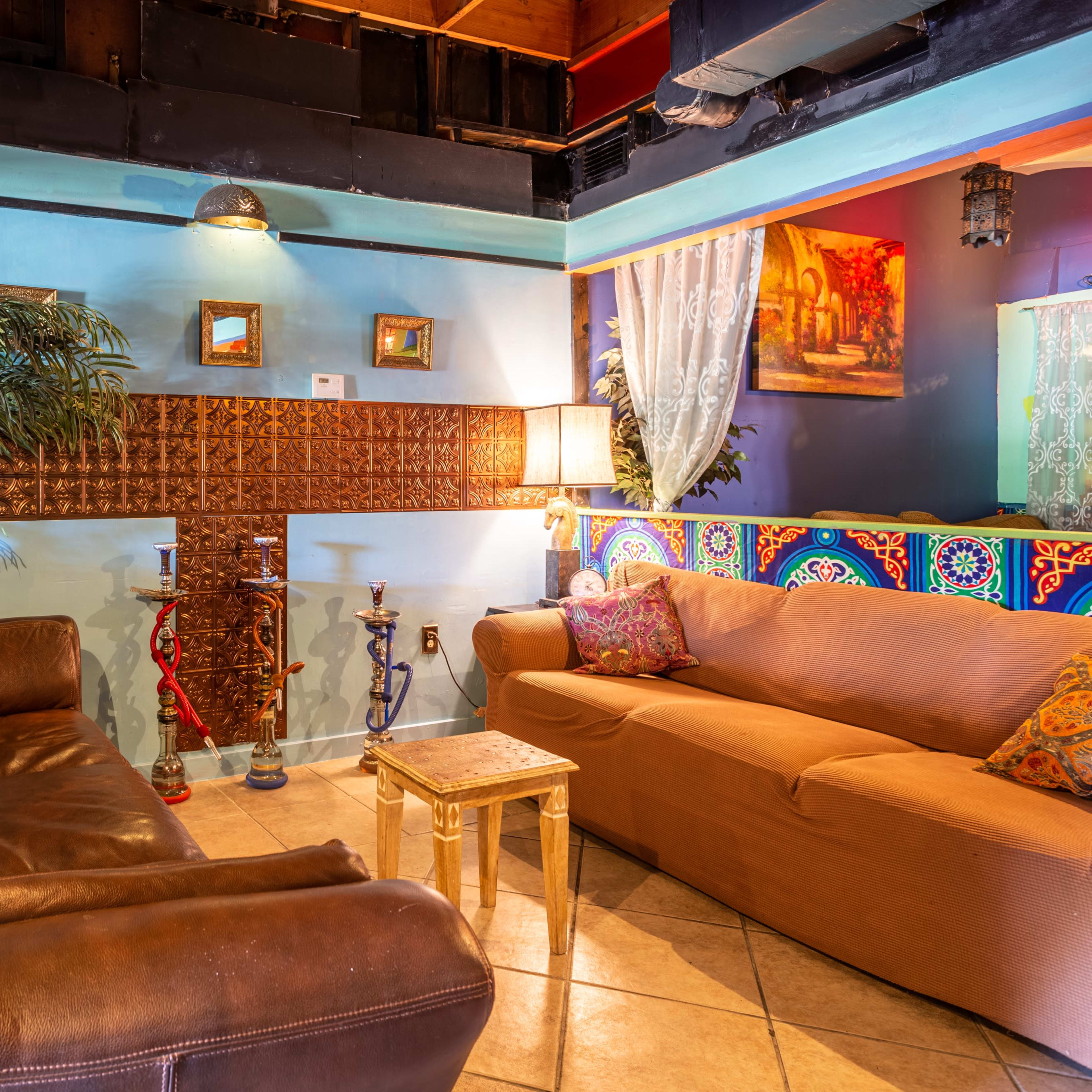 A cozy seating area with two sofas, a small table, and decorative walls featuring vibrant colors and patterns.