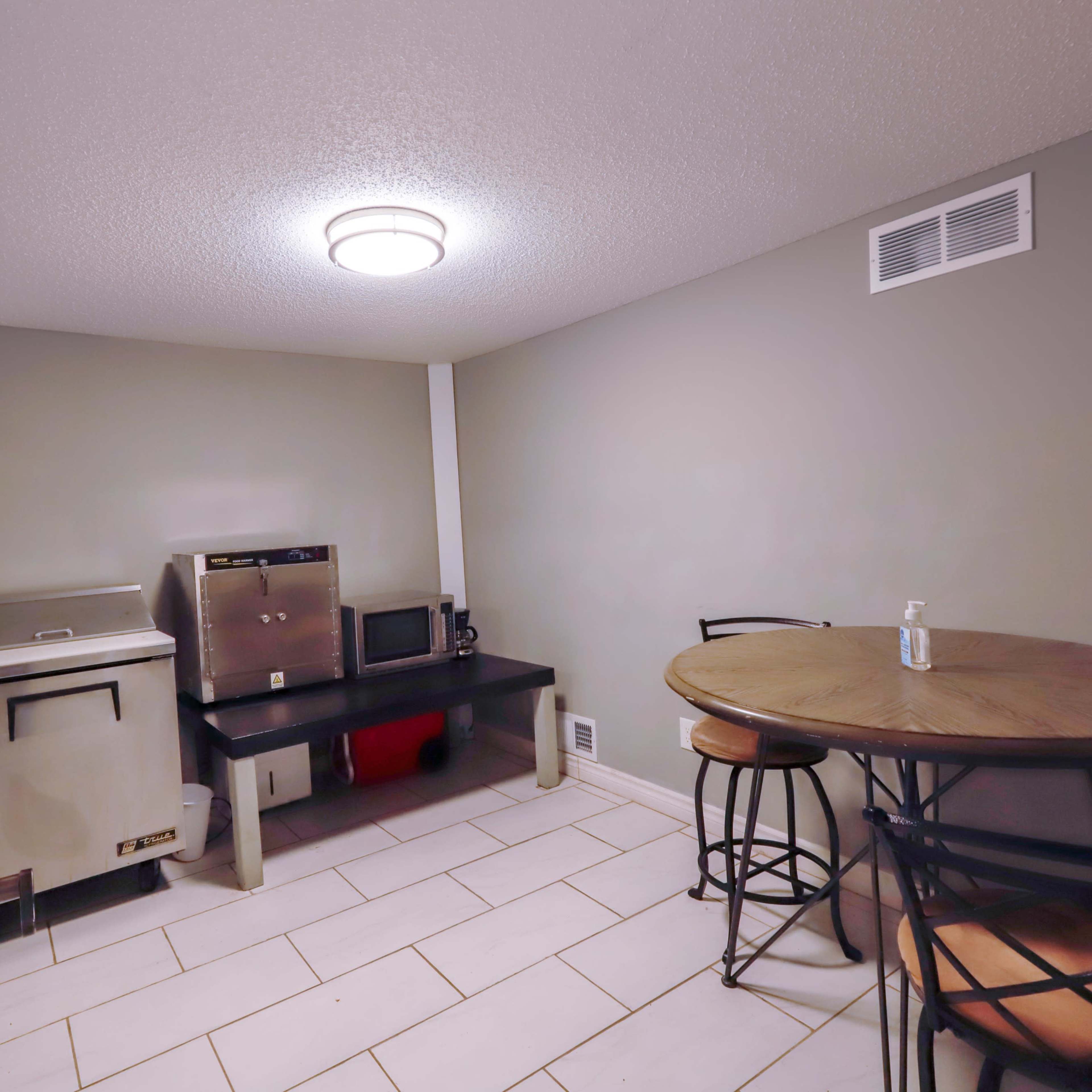 A small kitchen area with a table and chairs, a sink, and various appliances against the walls.