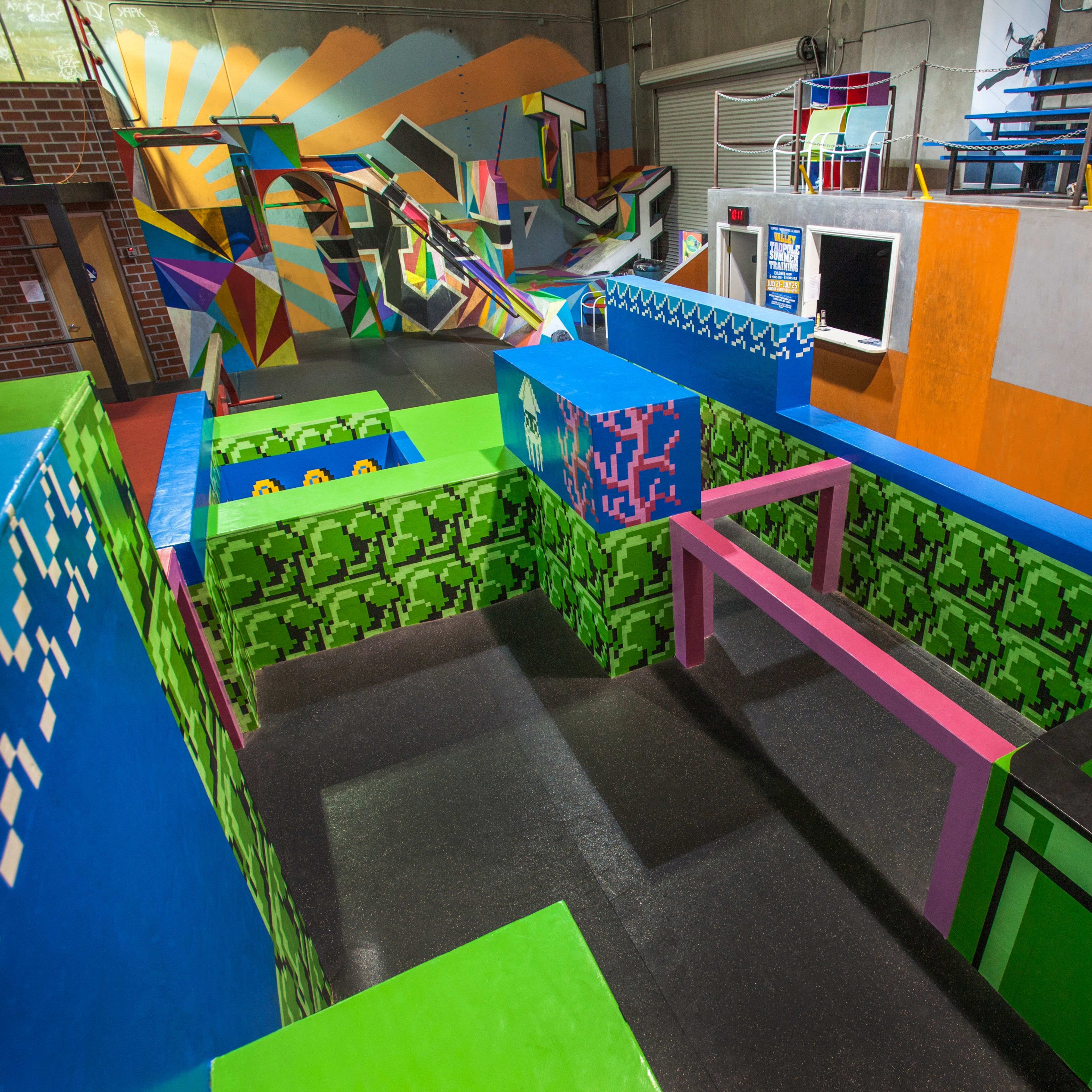 A colorful indoor parkour and obstacle course with various geometric shapes and painted walls.