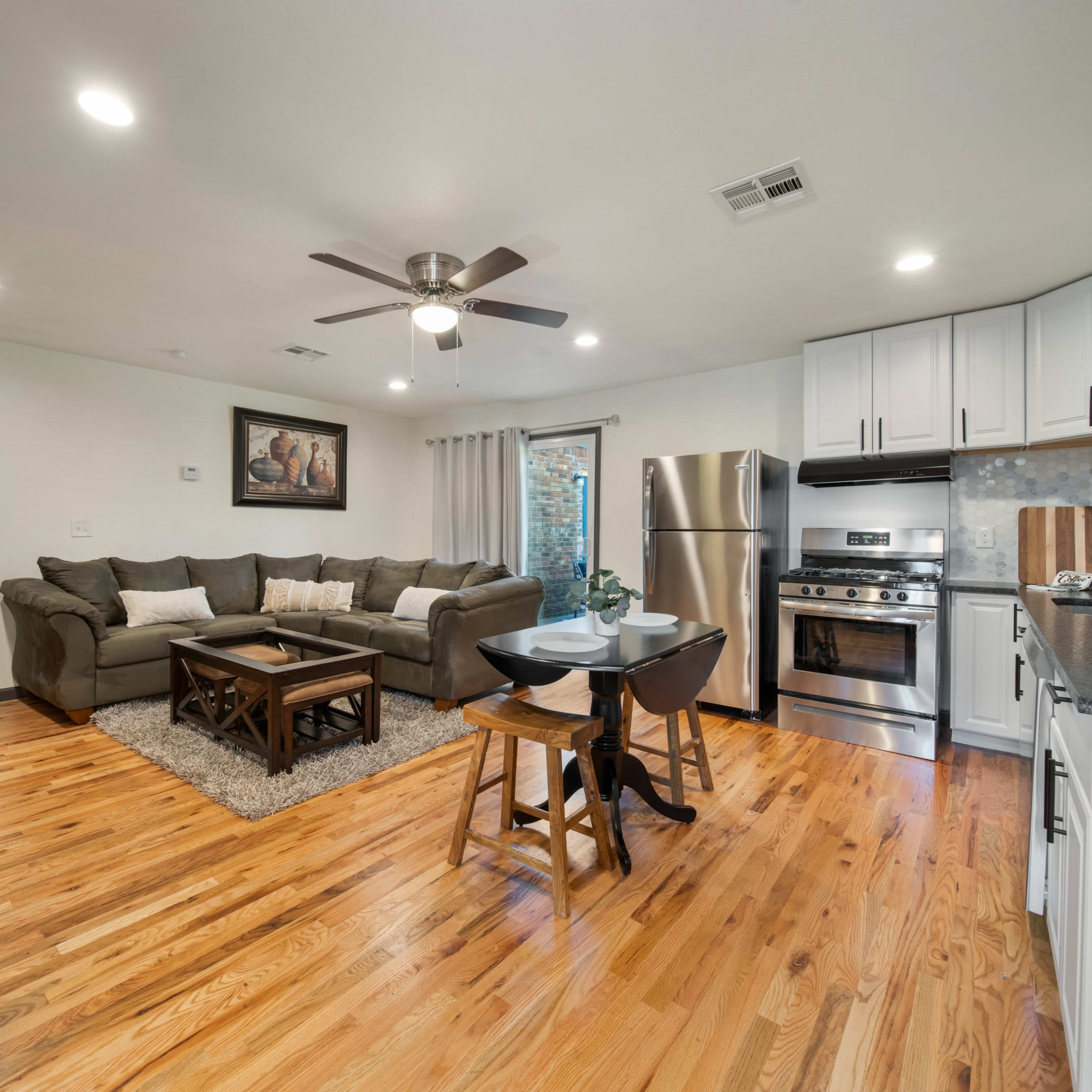 A modern kitchen and living area with a sofa, dining table, and stainless steel appliances.