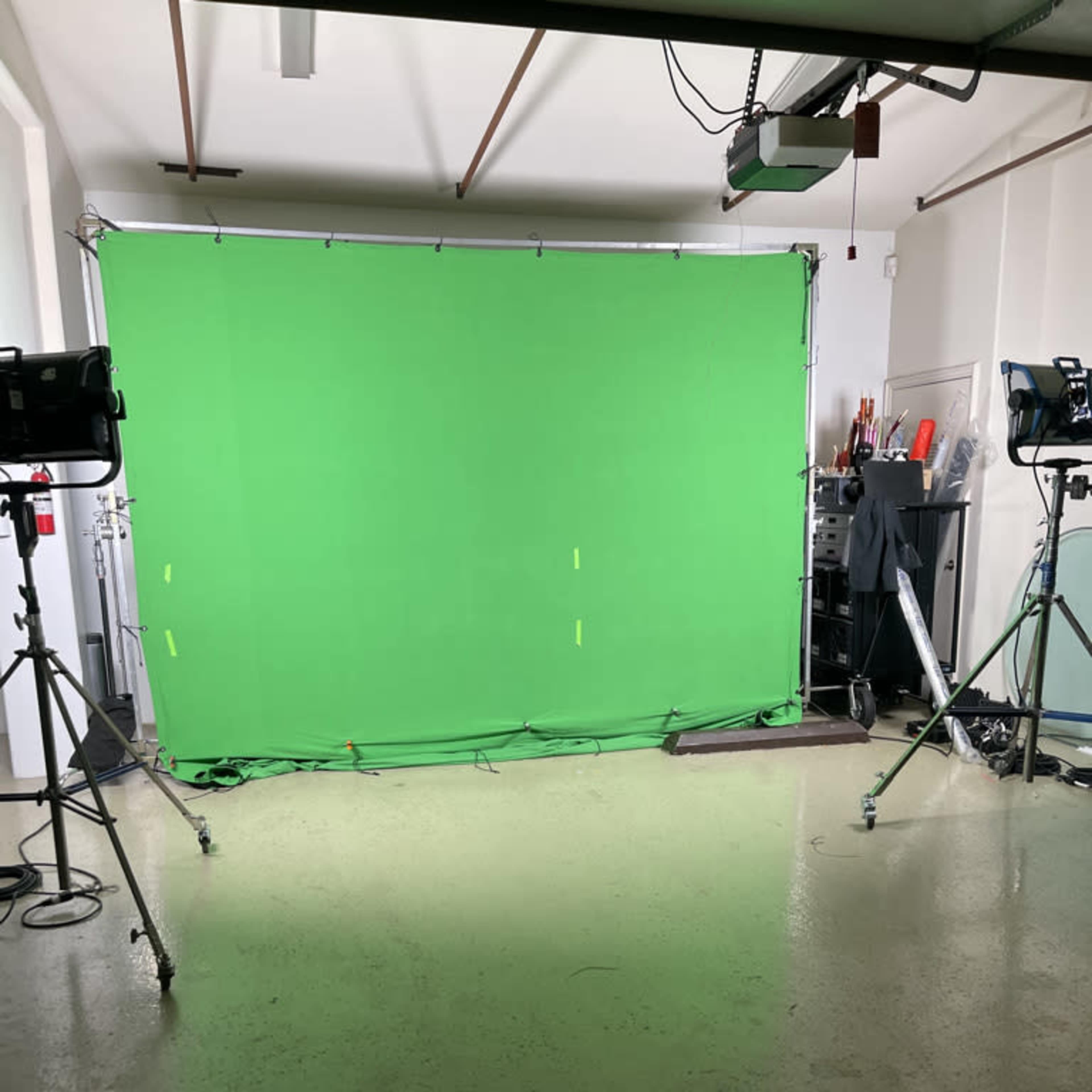 A green screen setup in a studio with lighting equipment positioned on either side.