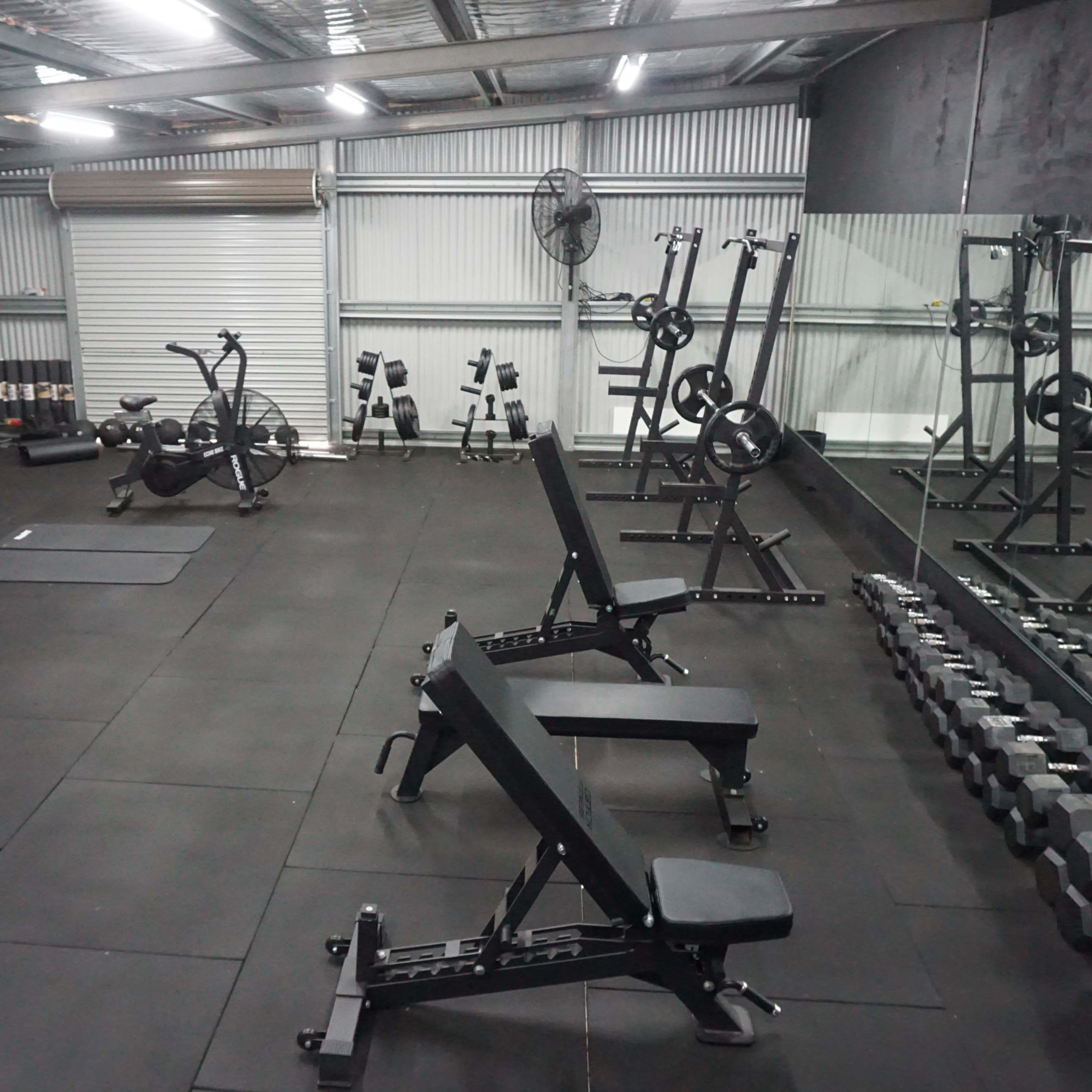 A fitness gym equipped with exercise machines, weights, and a mirror on one wall.