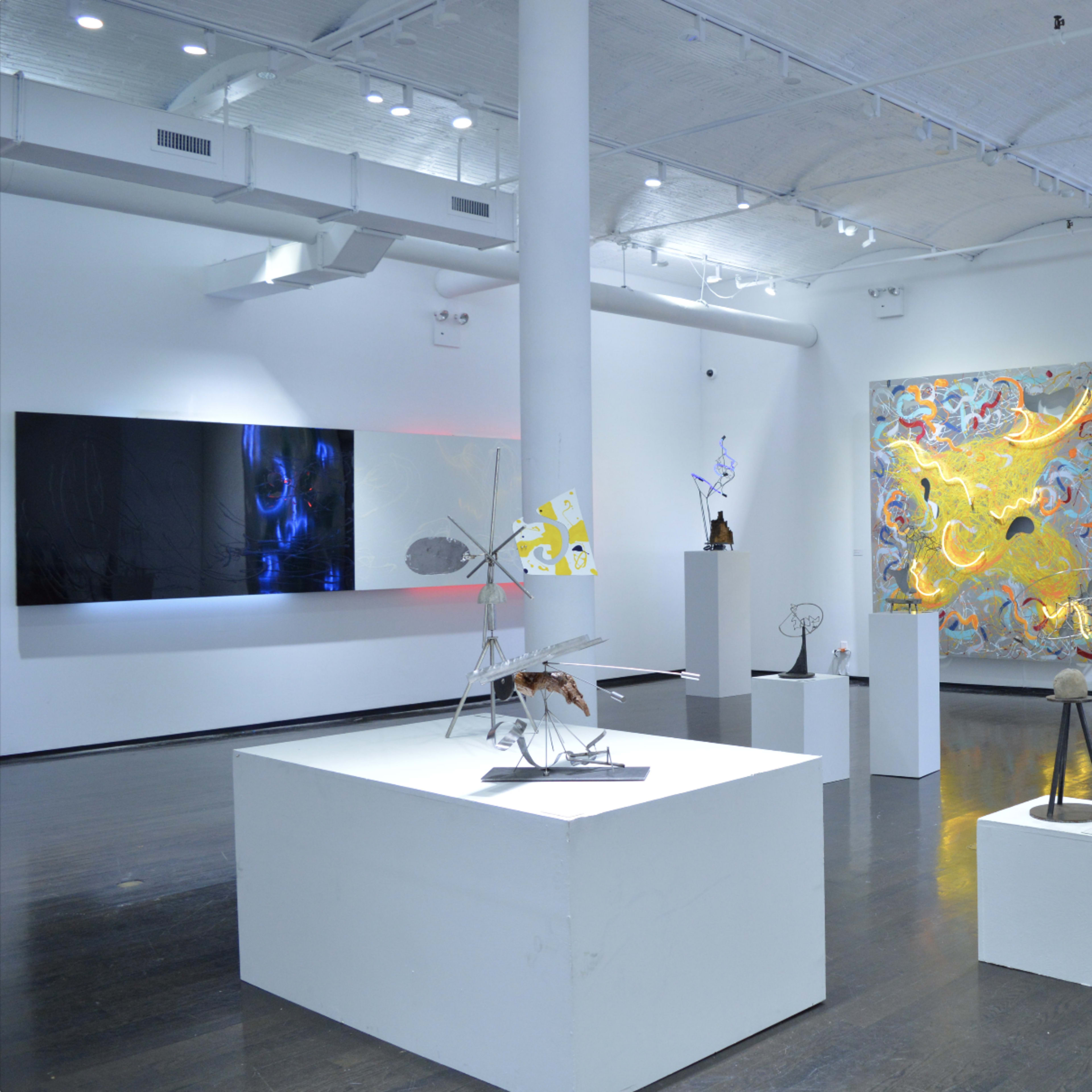 A contemporary art gallery featuring various sculptures and large abstract paintings on the walls.