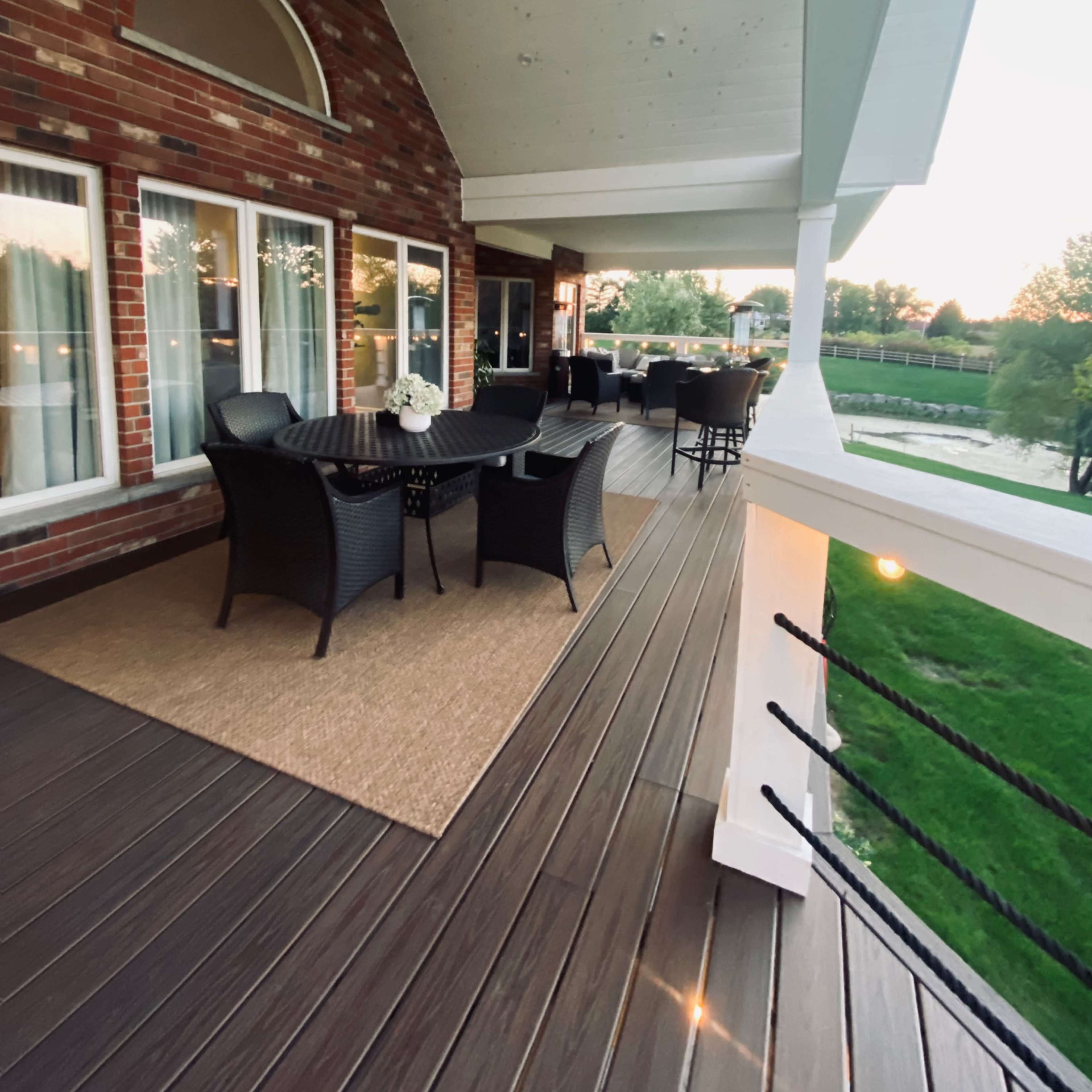 A spacious outdoor patio with wicker furniture and a view of a grassy area.
