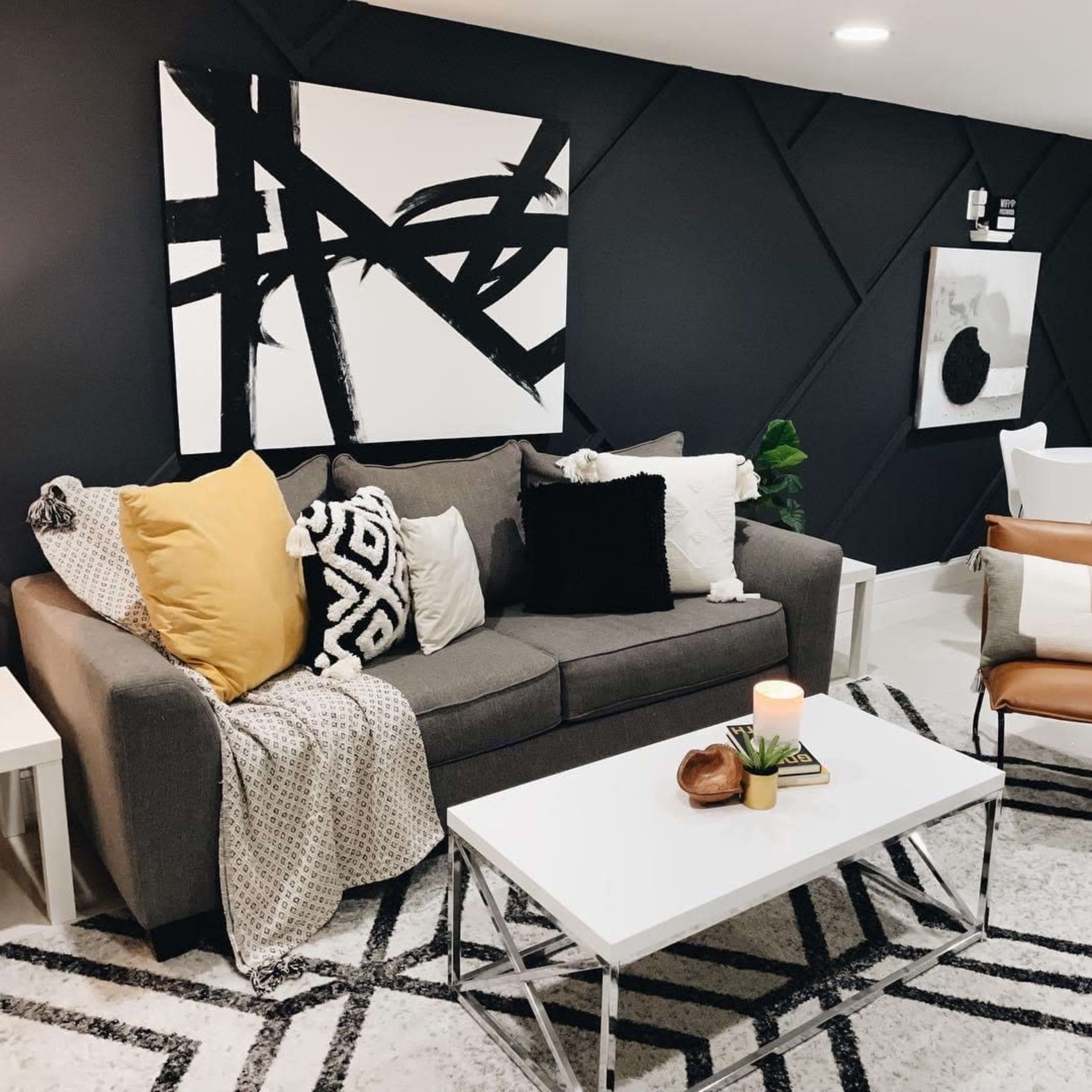 A modern living room with a gray sofa, decorative pillows, a coffee table, and a small dining area featuring a round table and chairs.