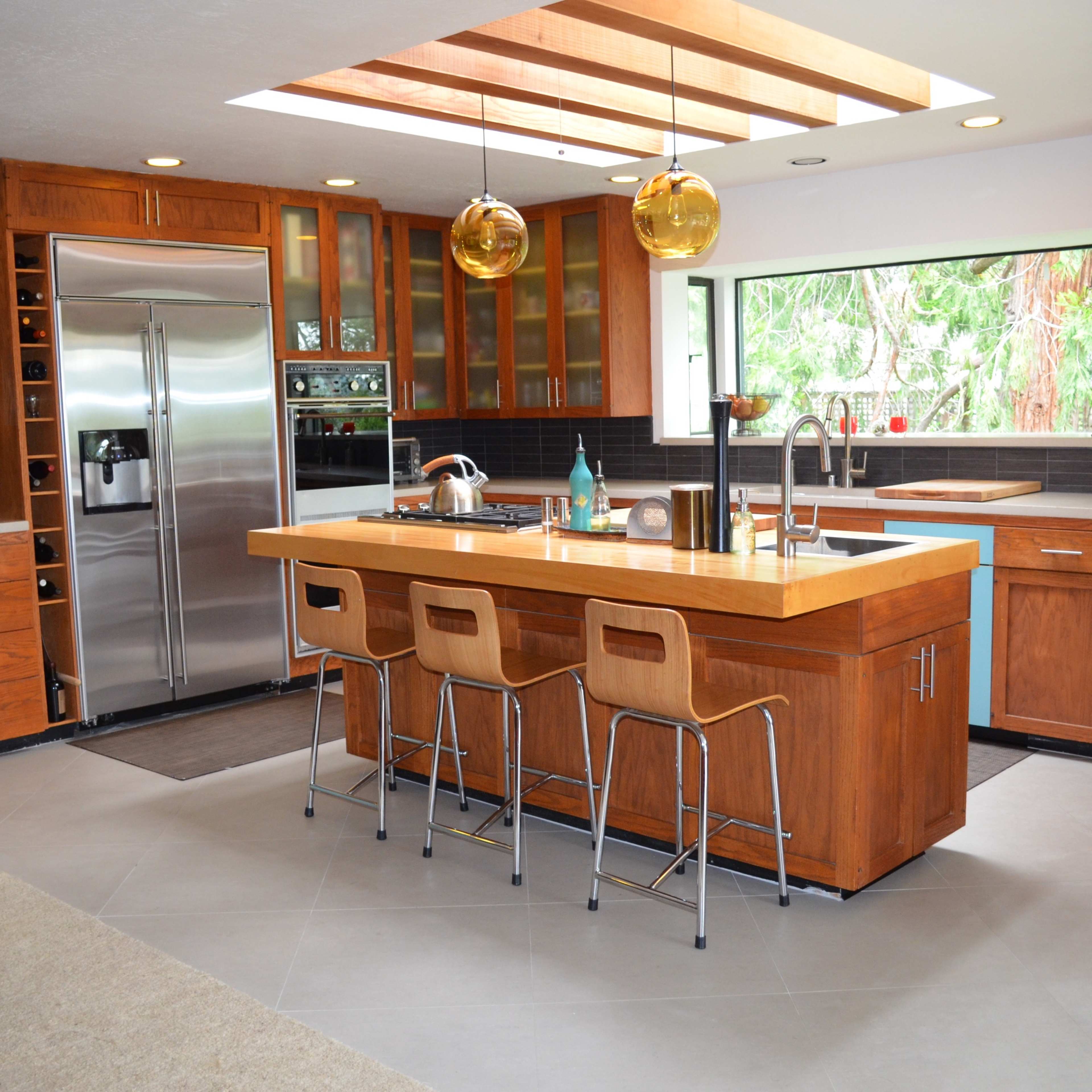 A modern kitchen with wooden cabinetry, a large island with seating, and stainless steel appliances.