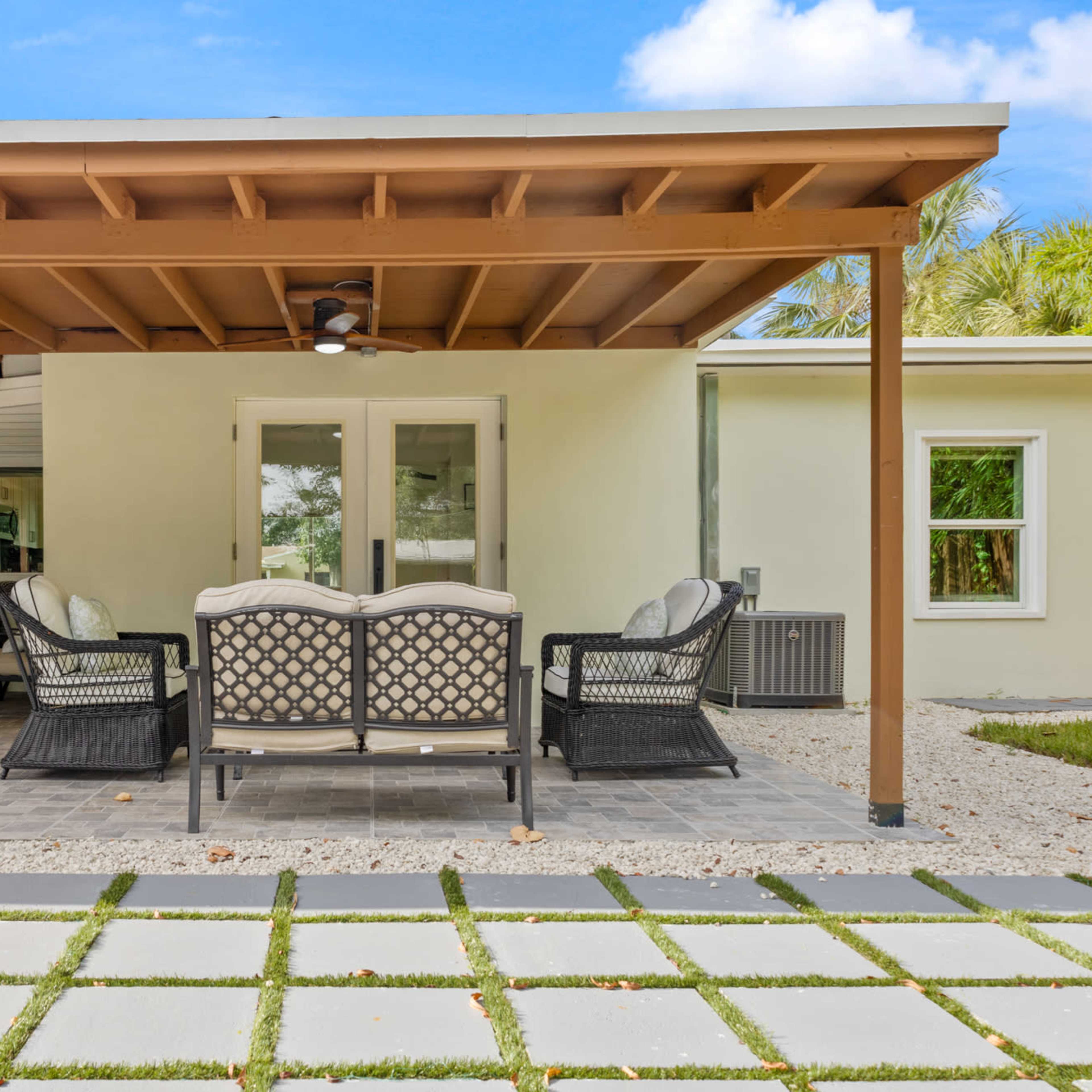 A patio area with seating furniture, a stone walkway, and a light-colored house in the background.