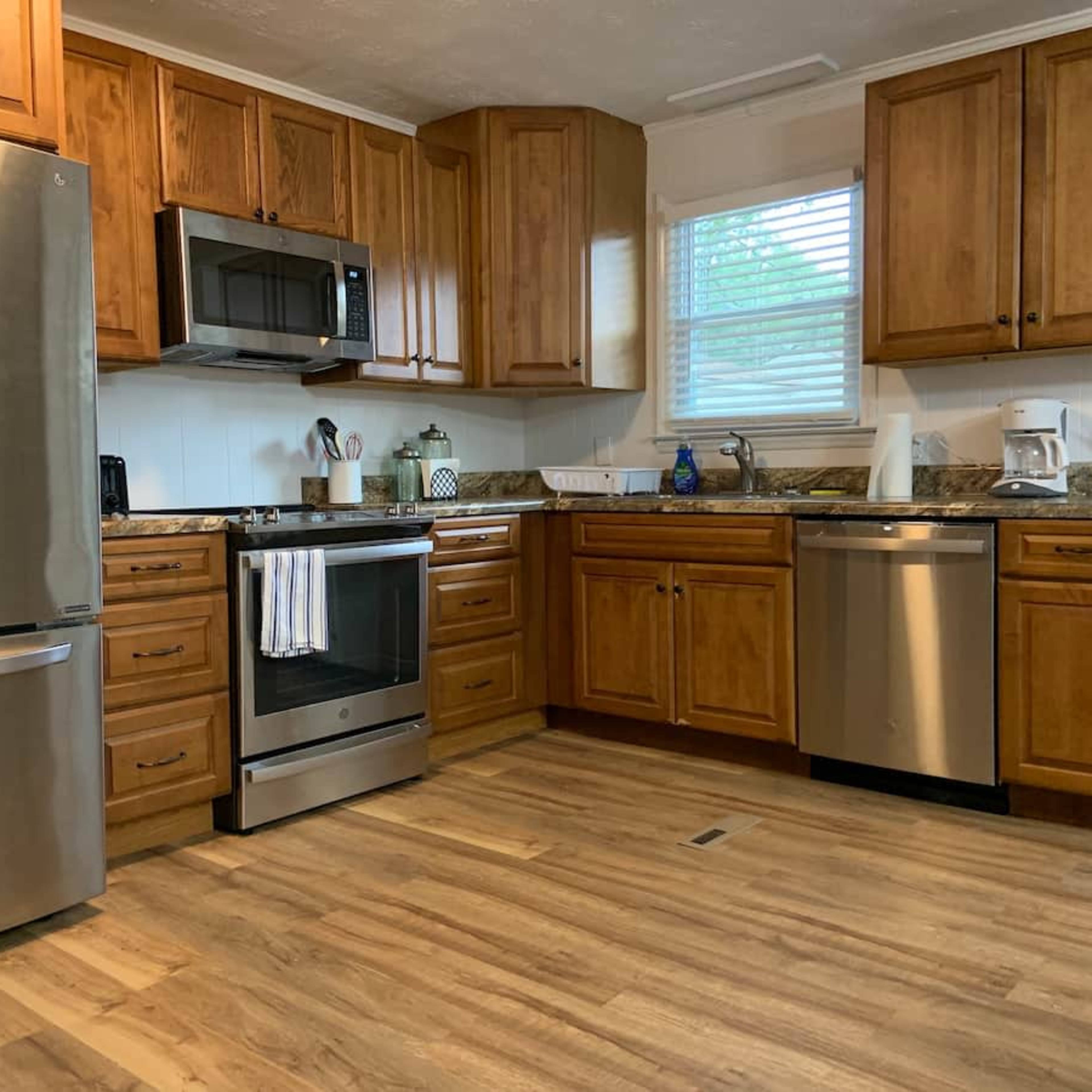 A kitchen with wooden cabinets, stainless steel appliances, and a light wood floor.