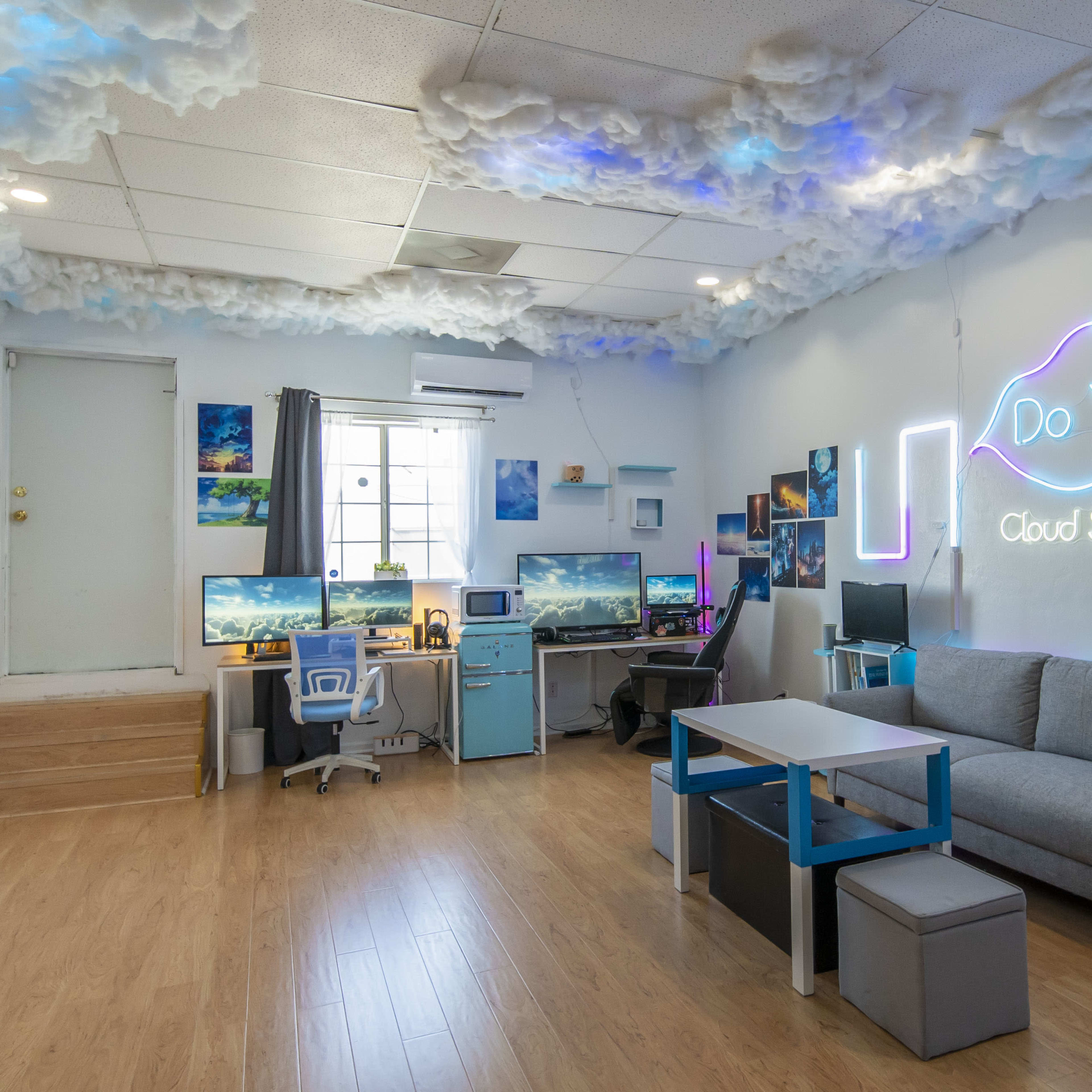 A modern cloud-themed studio featuring two computer desks, a couch, and decorative wall art, with a neon sign that says "Do Yu Cloud Studio."