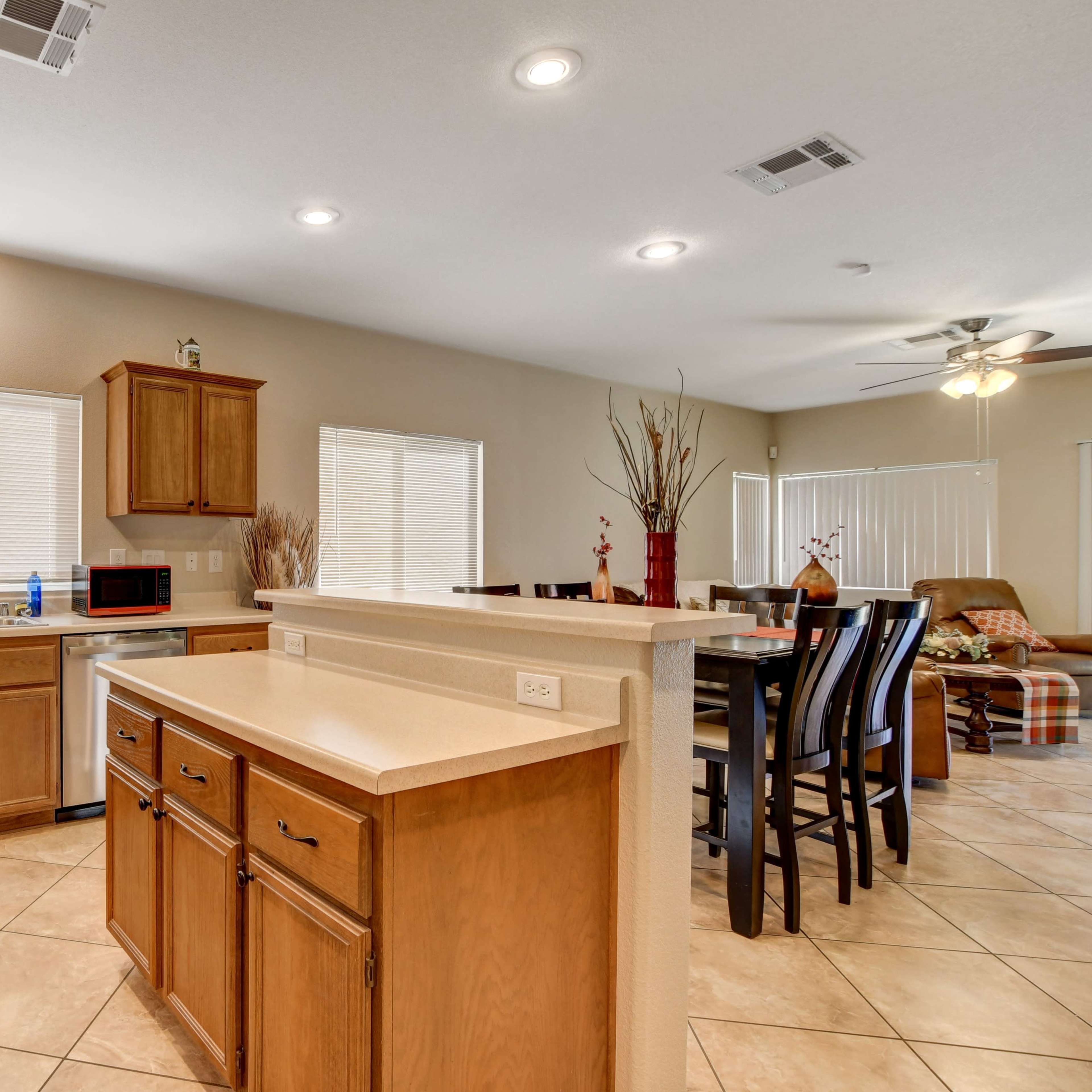 A spacious kitchen with wooden cabinets, a countertop island, and a dining area featuring a large table and chairs.