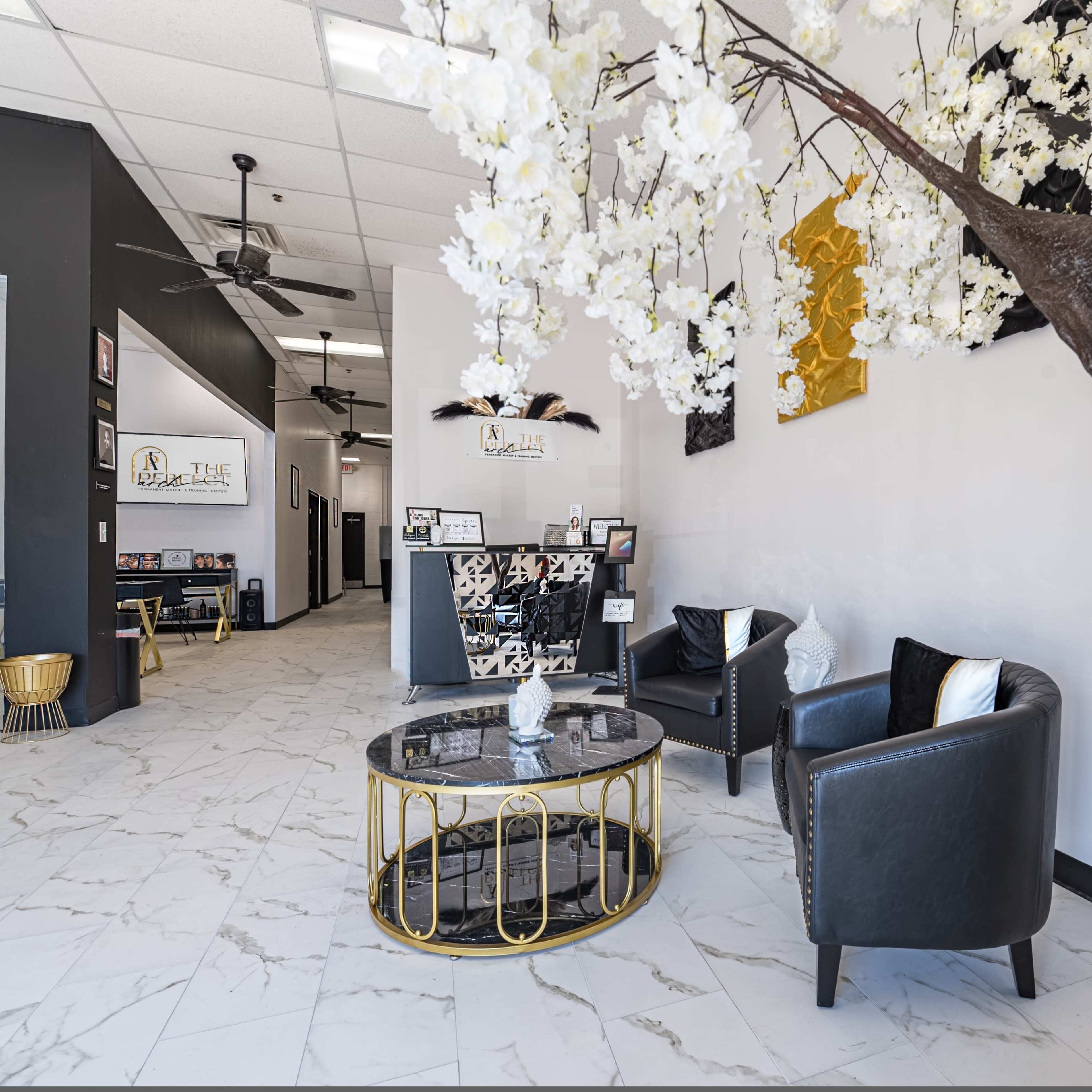 A modern reception area with a floral tree centerpiece, black seating, and marble flooring.