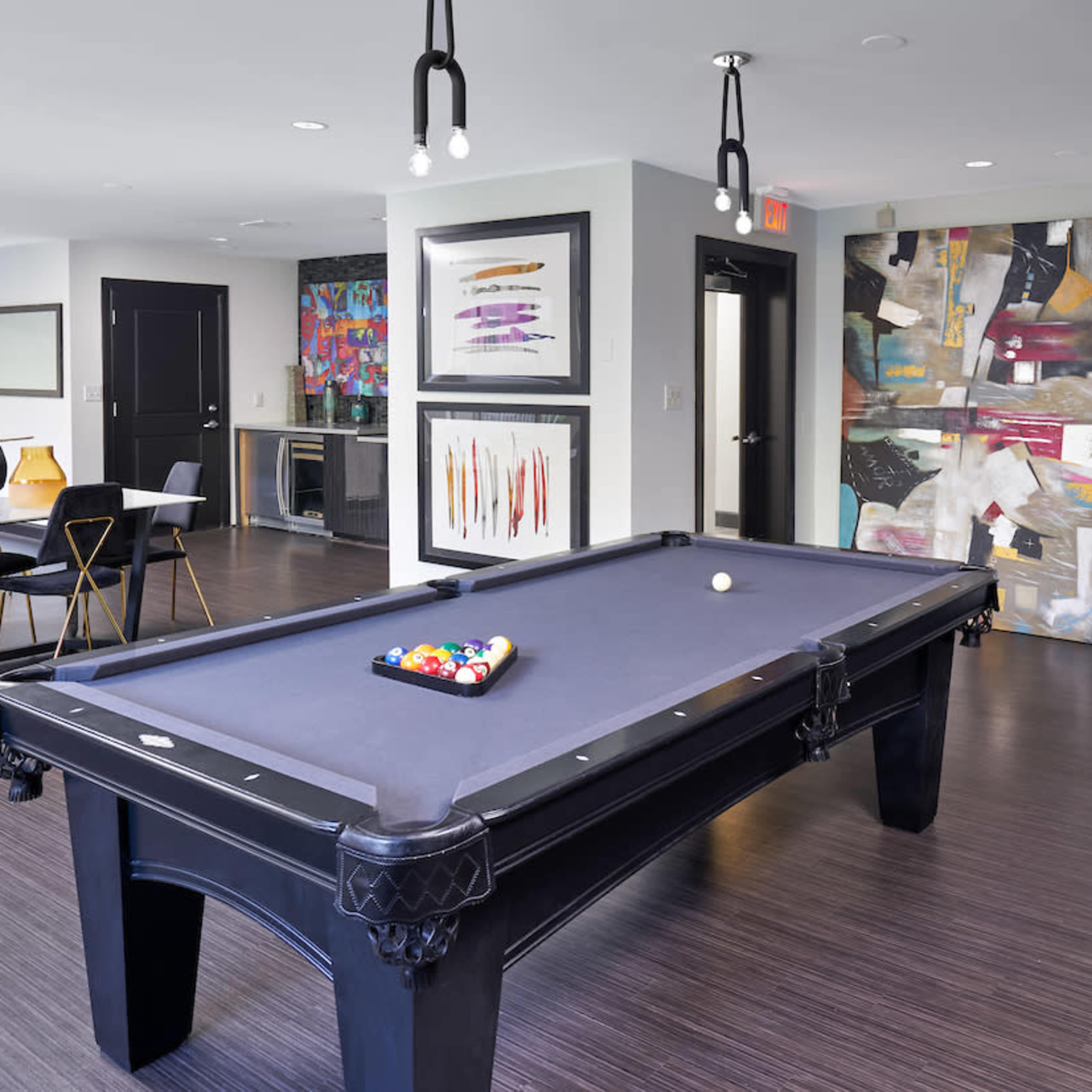 A modern recreational room featuring a billiards table, dining area, and abstract artwork on the walls.