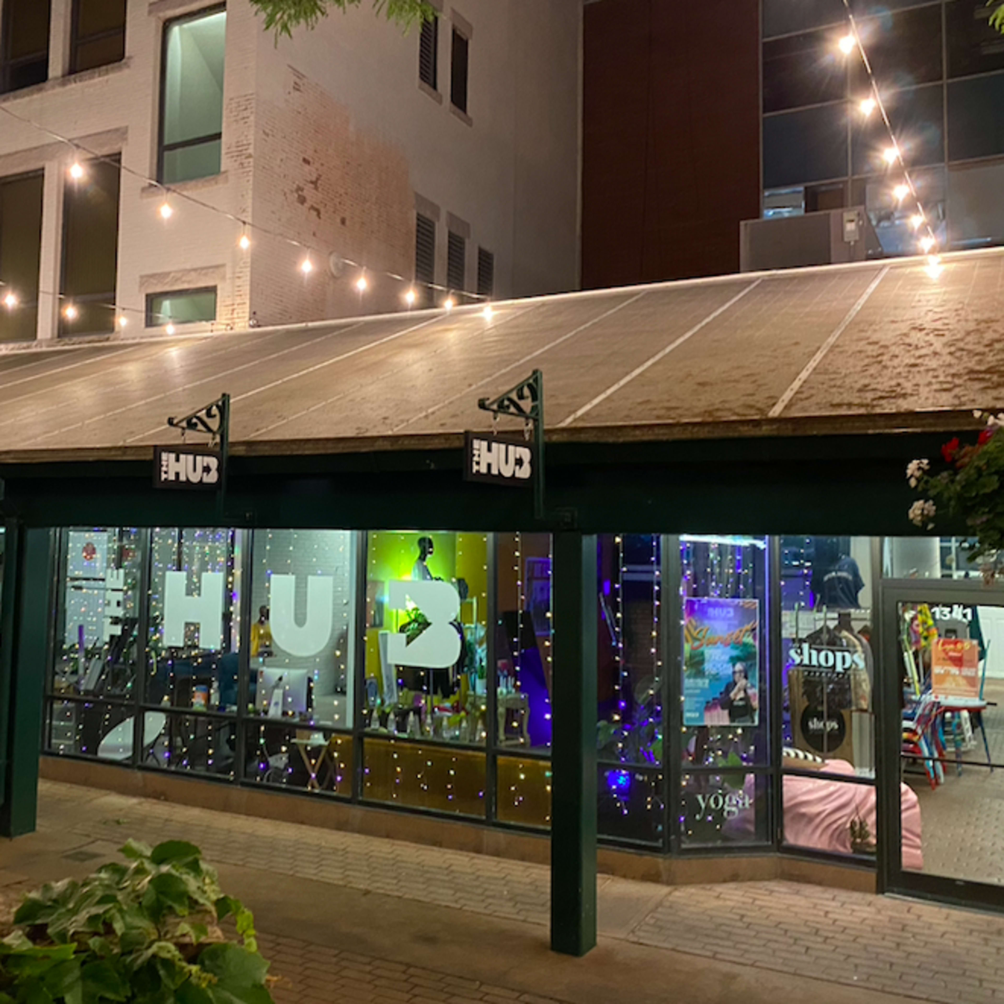 A lit storefront with large windows displaying the word "HUD" and colorful decorations inside.